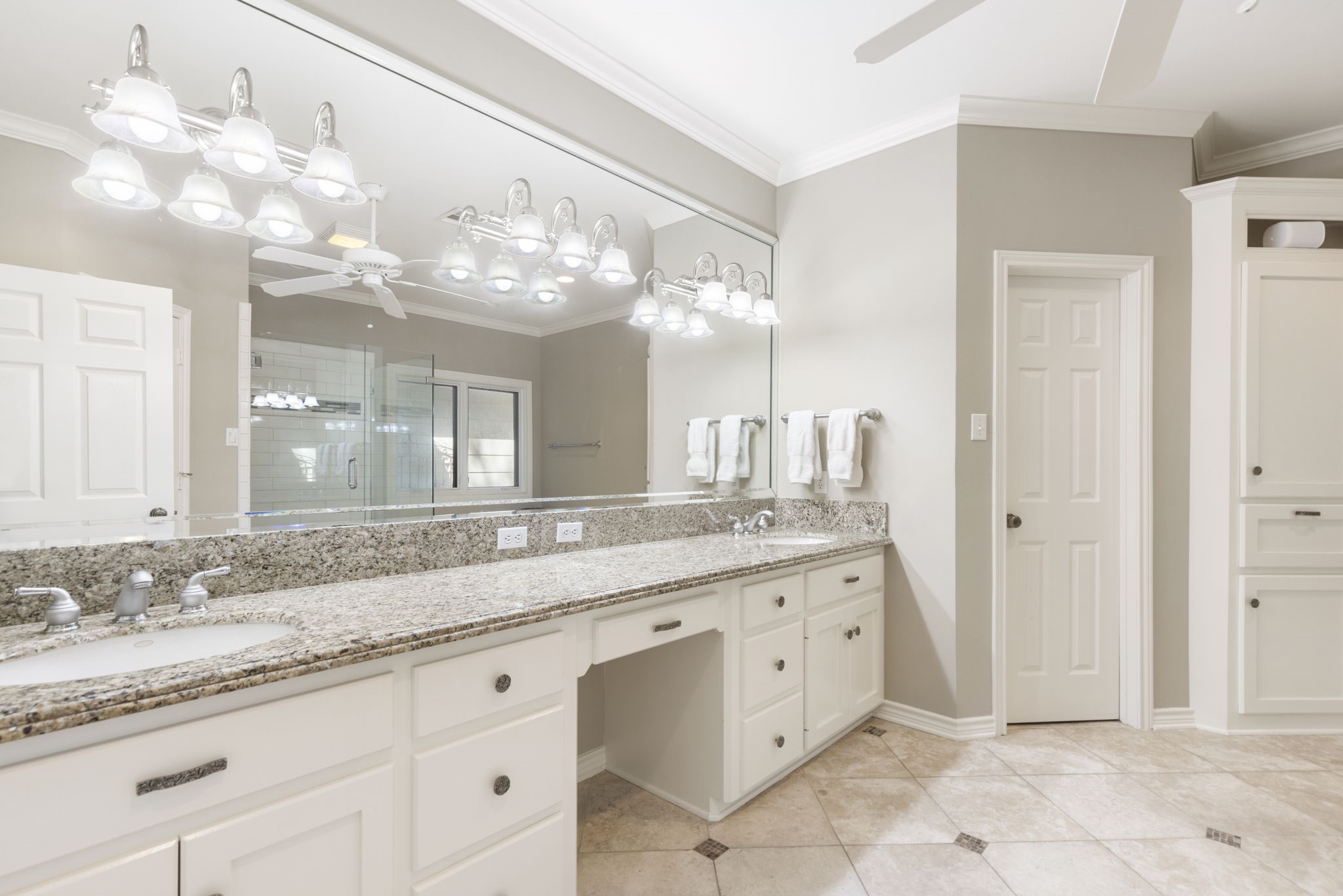 Expansive counter space, abundant drawers, and a broad mirror make the primary vanity especially accommodating.