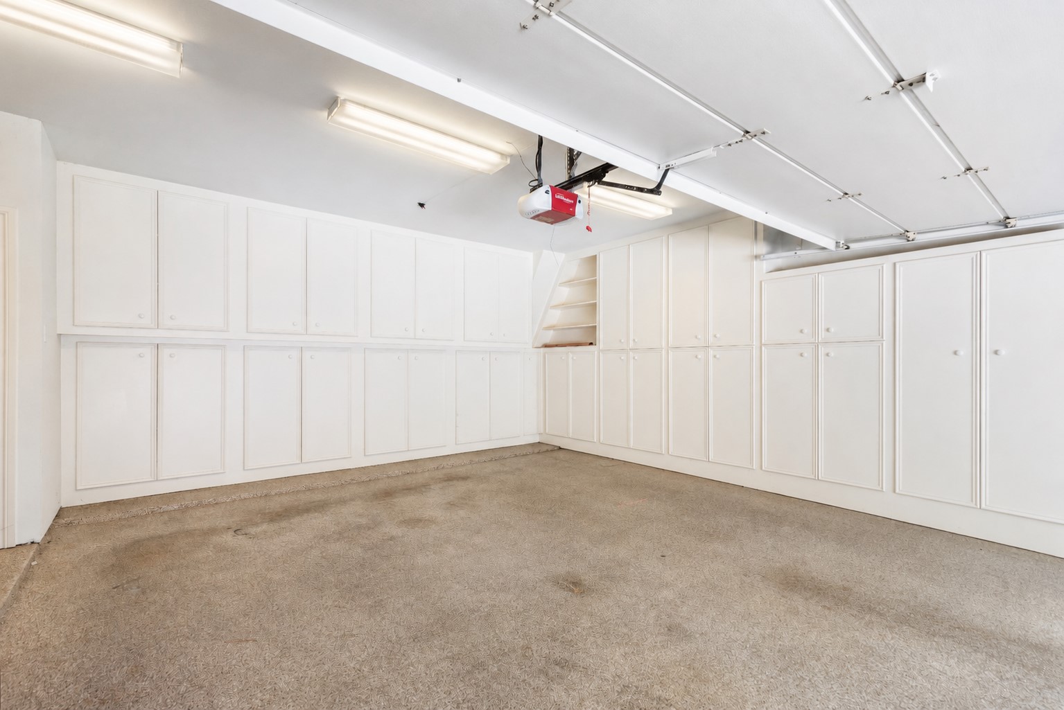 Extensive enclosed garage cabinetry keeps tools, supplies, and seasonal belongings neatly tucked away. The other side of garage has even more storage and built-ins.