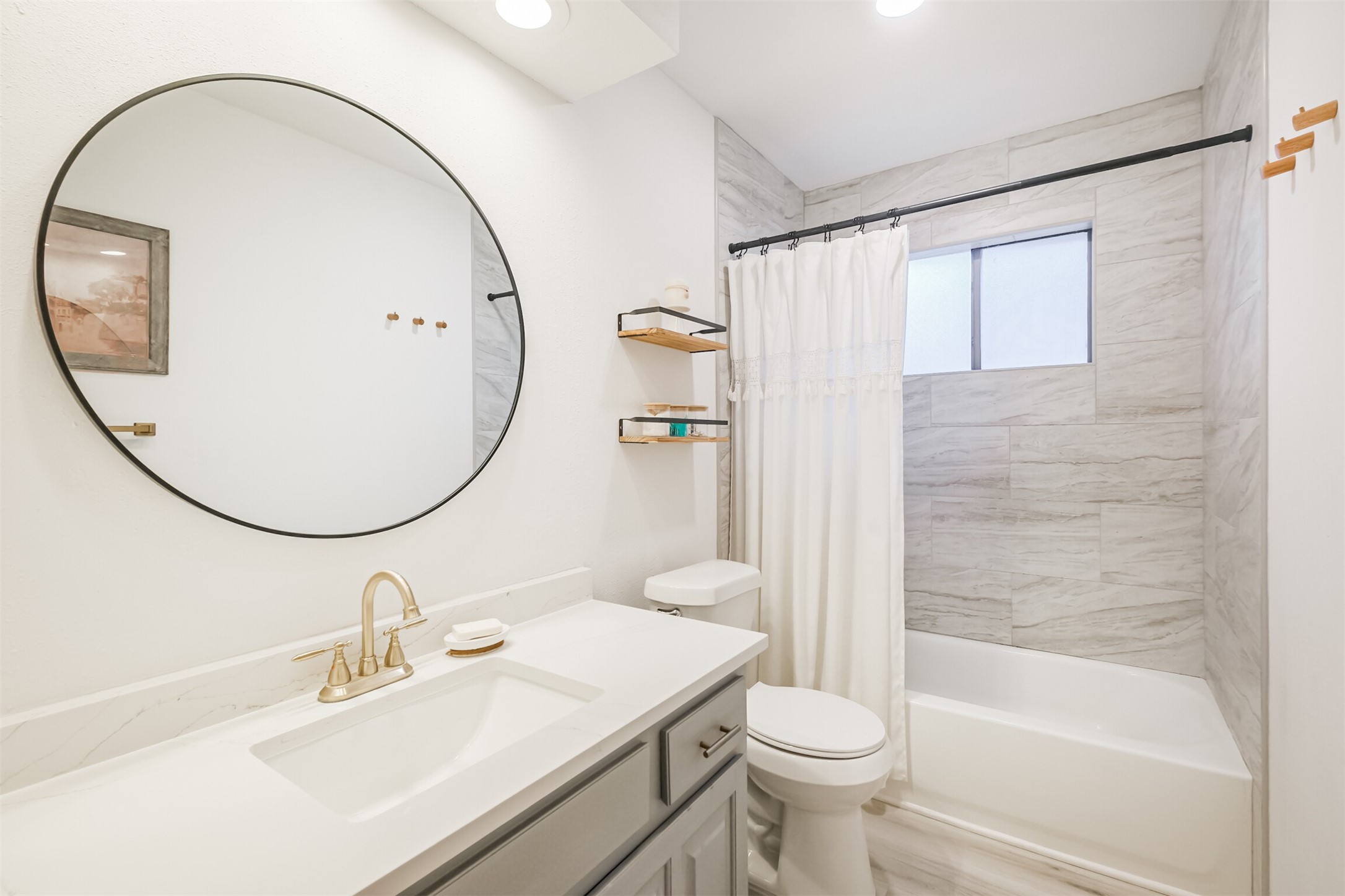 The second full bathroom has been updated with quartz counters, gold faucet and a tub+shower duo with tile surround.