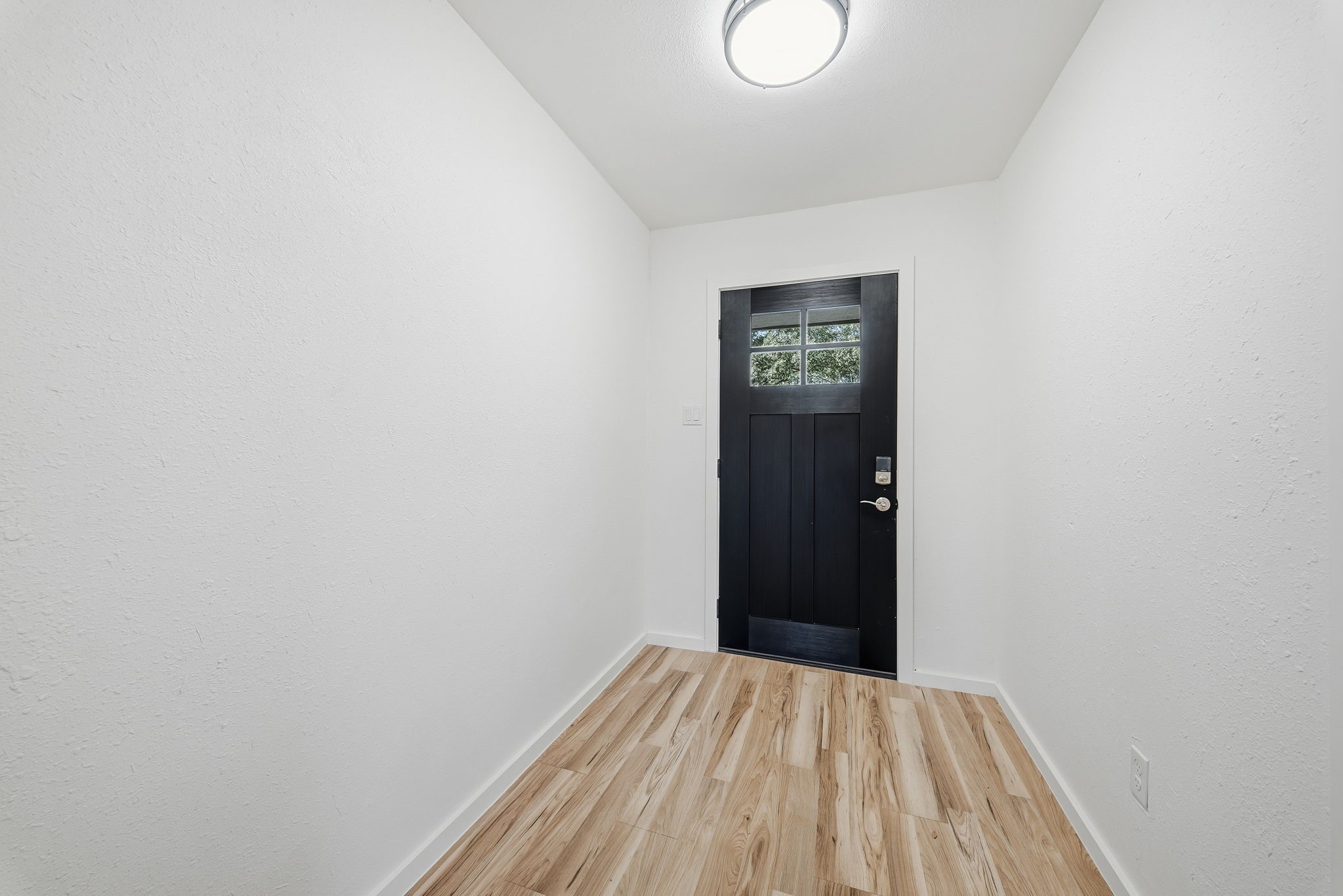 Foyer entry with a modern black front door and a keypad lock.
