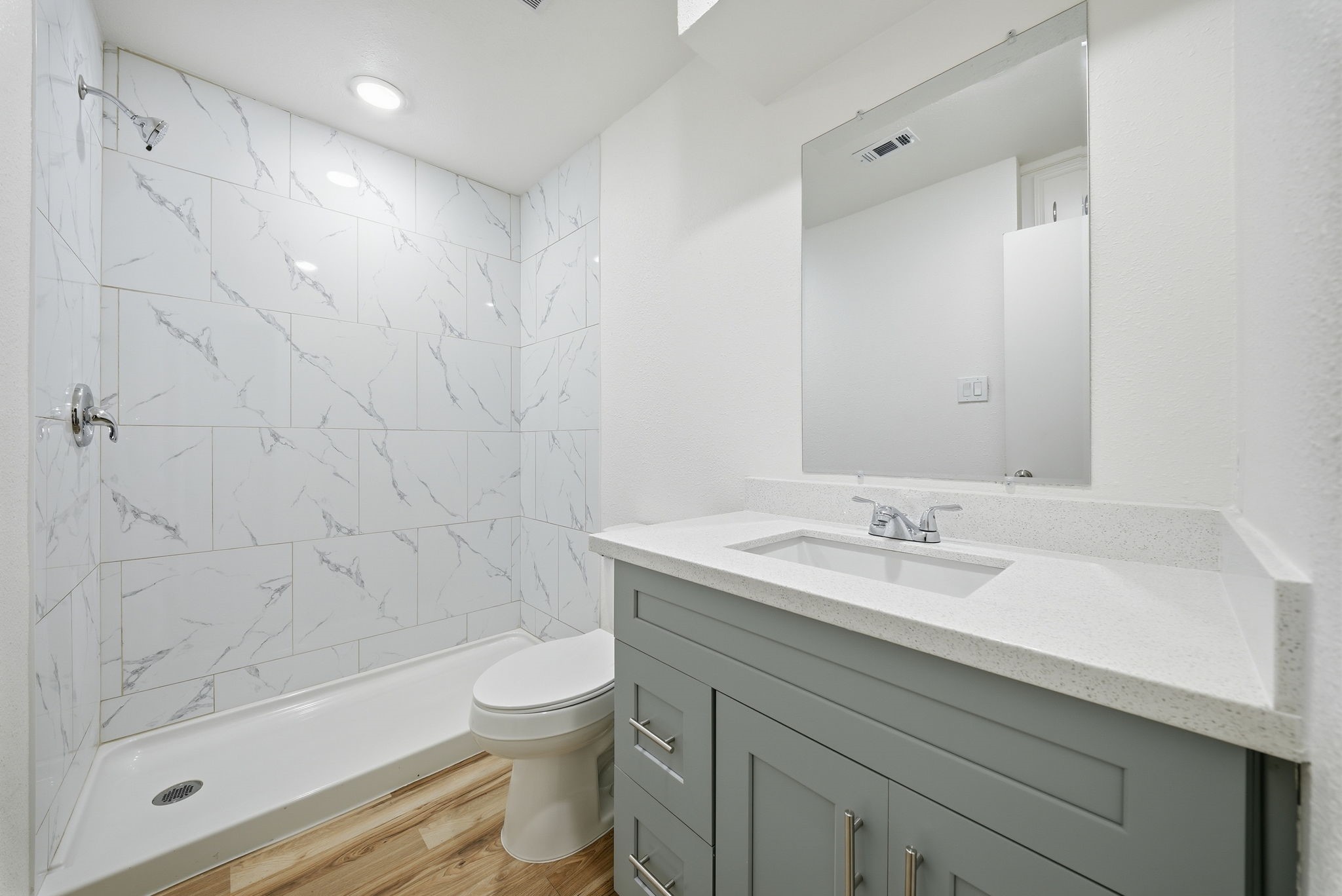 Hall bath with a tiled walk-in shower and a shaker vanity with storage drawers.