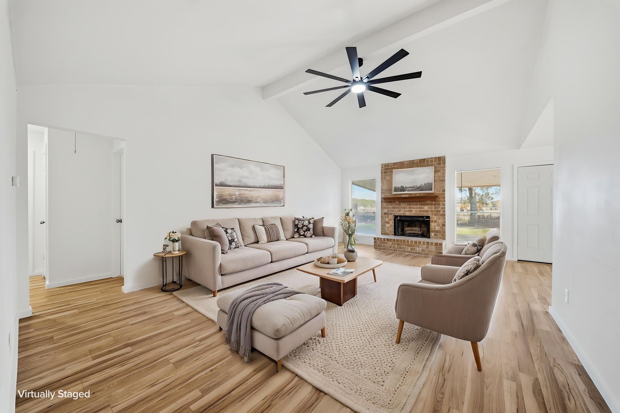 Virtually staged. Gather by the brick gas fireplace under a vaulted, beamed ceiling with yard views on both sides.