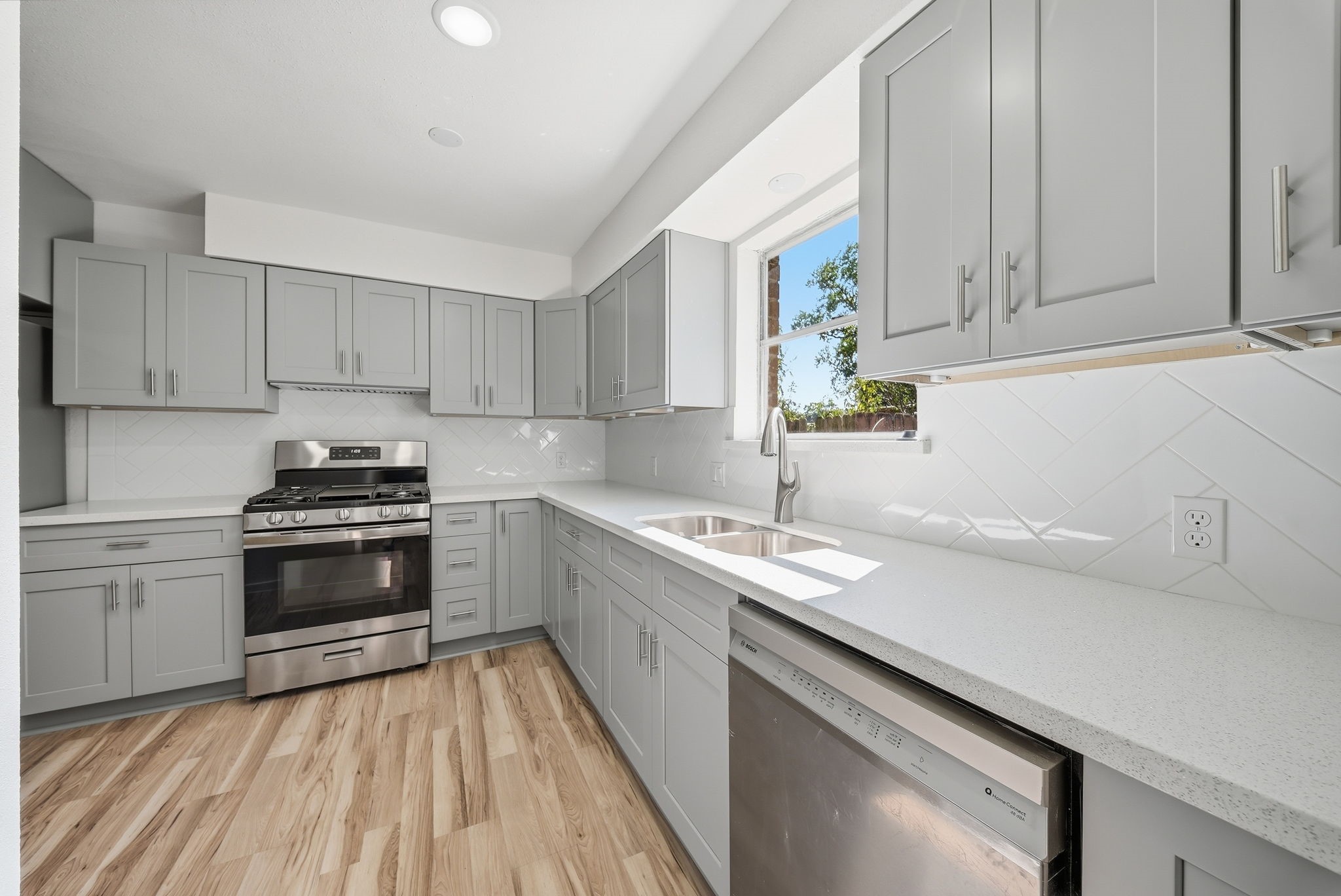 White counters, diagonal tile backsplash and a dishwasher keep cleanup simple.