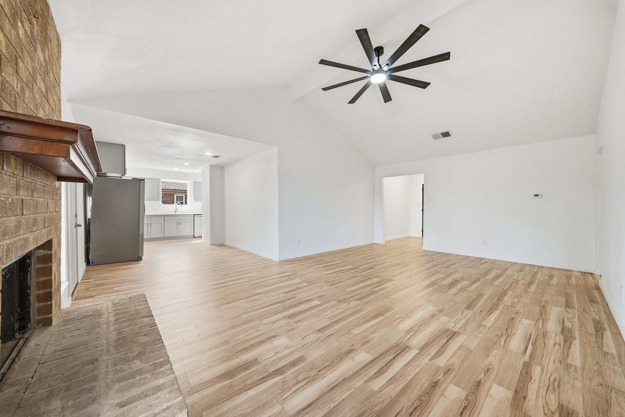 Living room flows straight into the kitchen and dining area, all on wood-look floors.