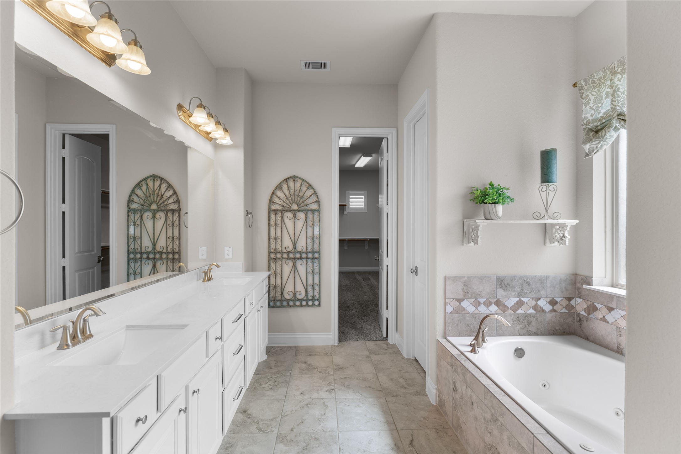 Spa-inspired primary bath with dual vanities, soaking tub, and oversized shower.