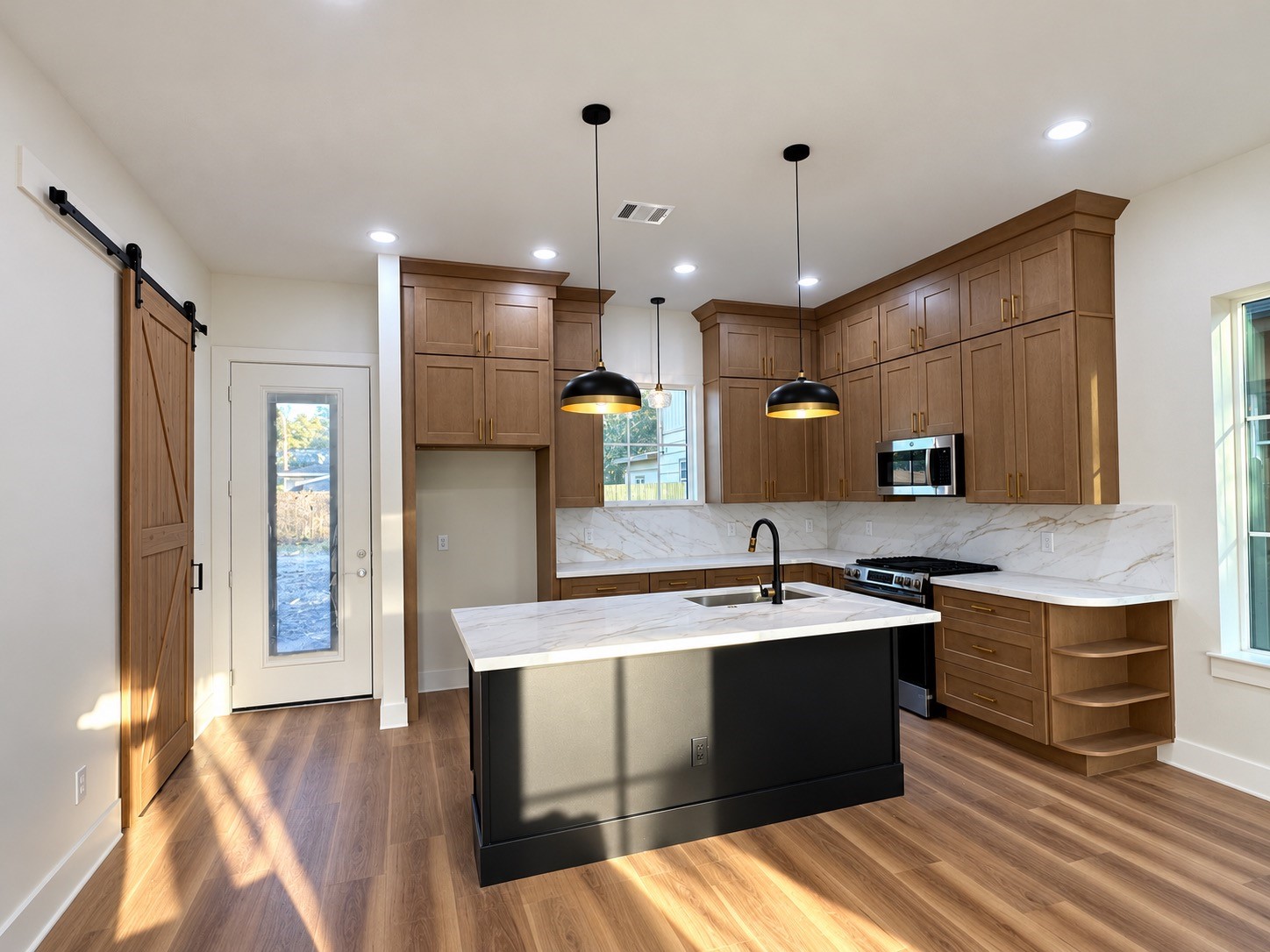 Thoughtfully designed kitchen featuring a
built in bookshelf, barn door pantry, ceiling height cabinetry, and an oversized island with plenty of room to move around and entertain. This photo has been virtually rendered based on the plans for this home.