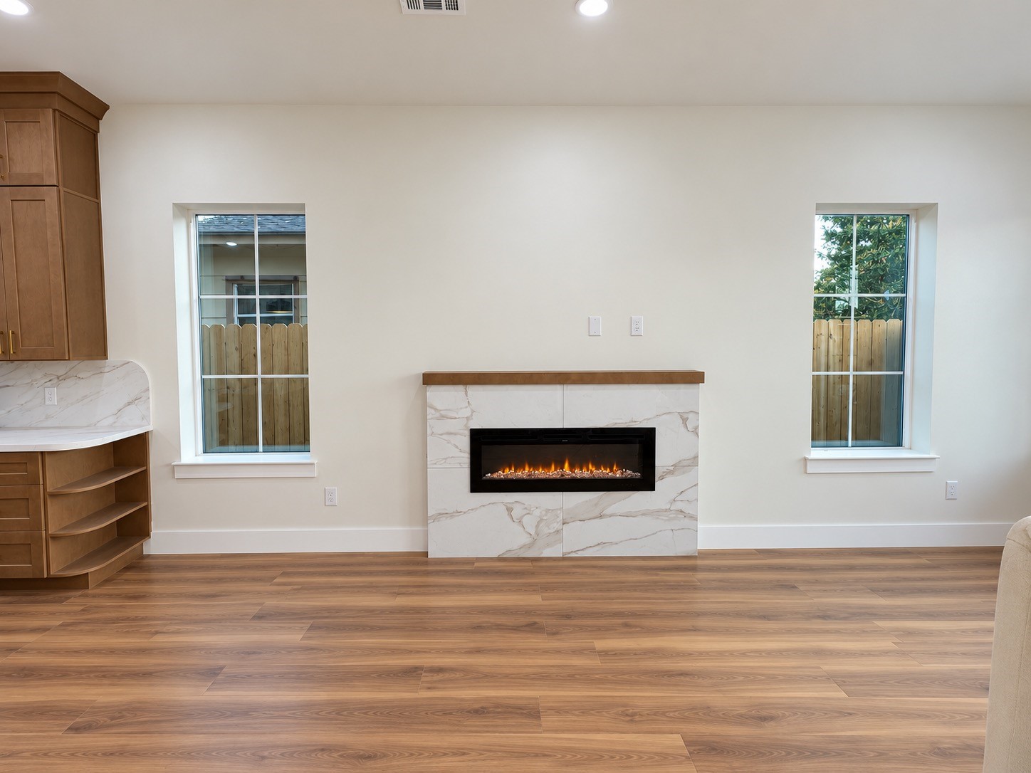 Chic living space featuring a modern electric fireplace and ample natural light from large windows.This photo has been virtually rendered based on the plans for this home.