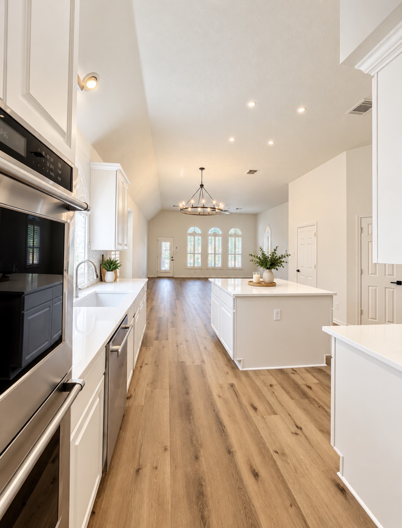 View of the kitchen, breakfast area, and family room.  The powder bath and third pantry are on each side behind where this photo is taken as well as the laundry room.
