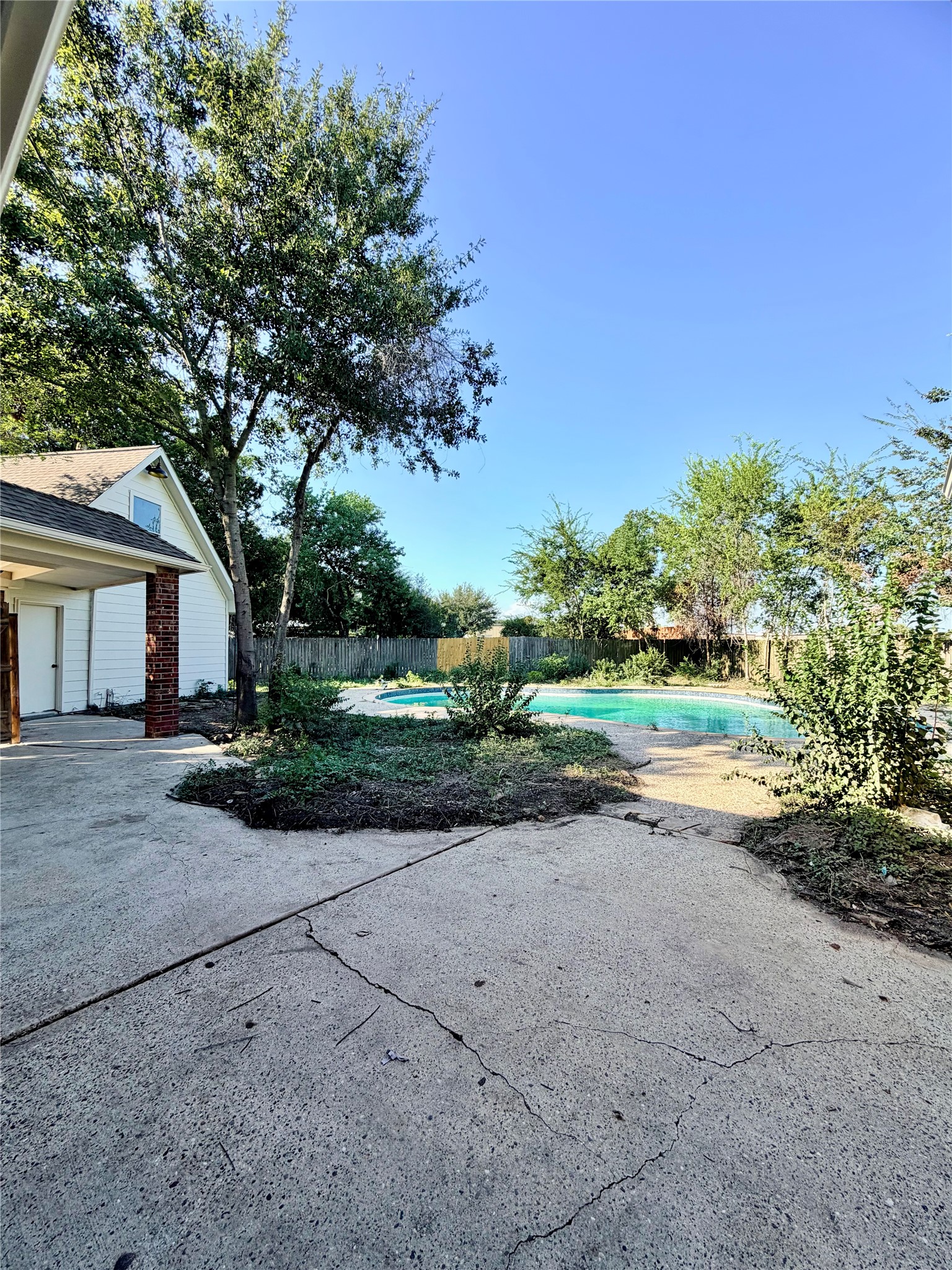 View from the covered back porch to the large pool and yard