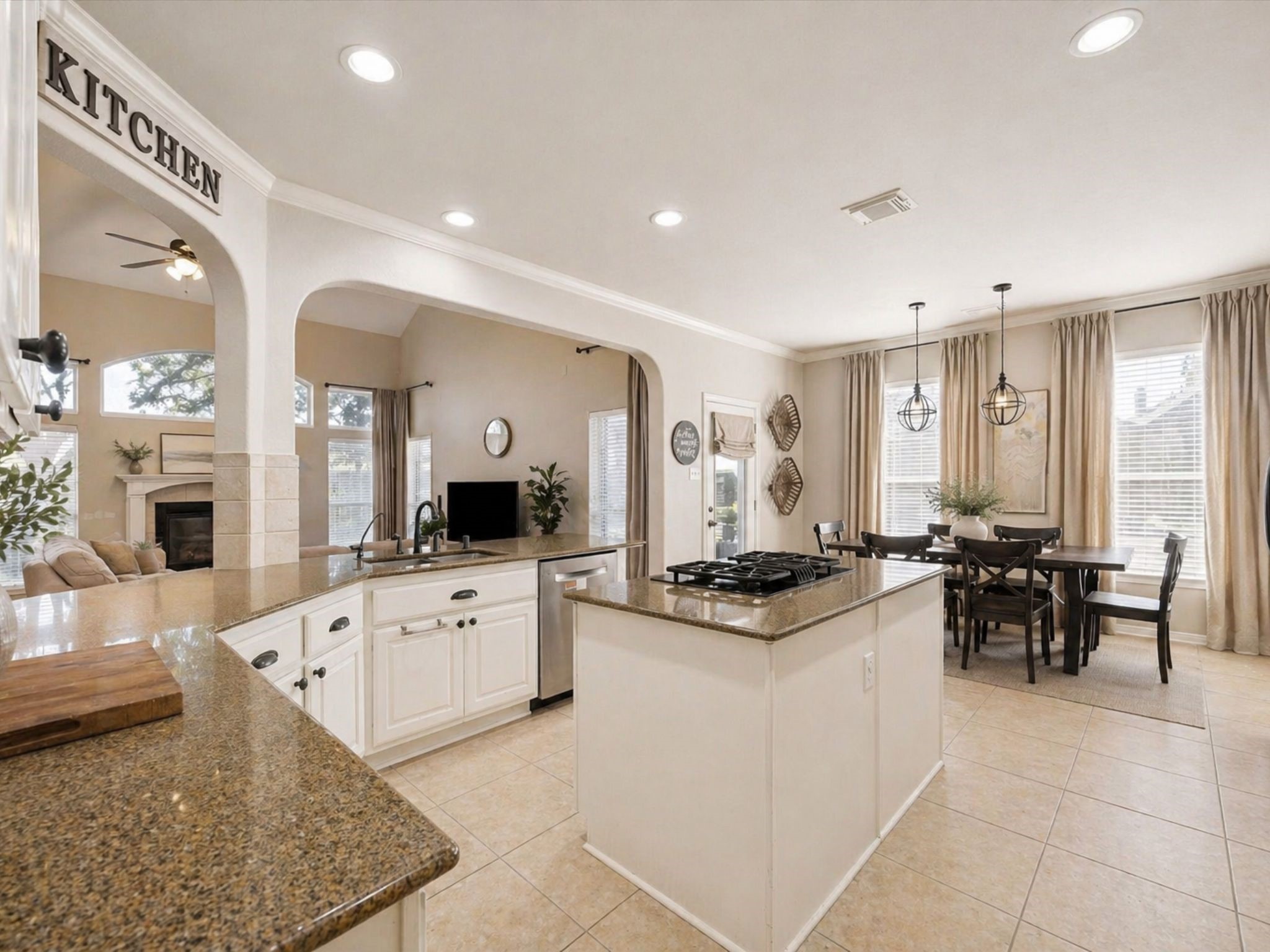 CHEF-STYLE KITCHEN FEATURING GRANITE COUNTERTOPS, GAS COOKTOP ISLAND, DOUBLE OVENS, AND EXTENSIVE STORAGE.