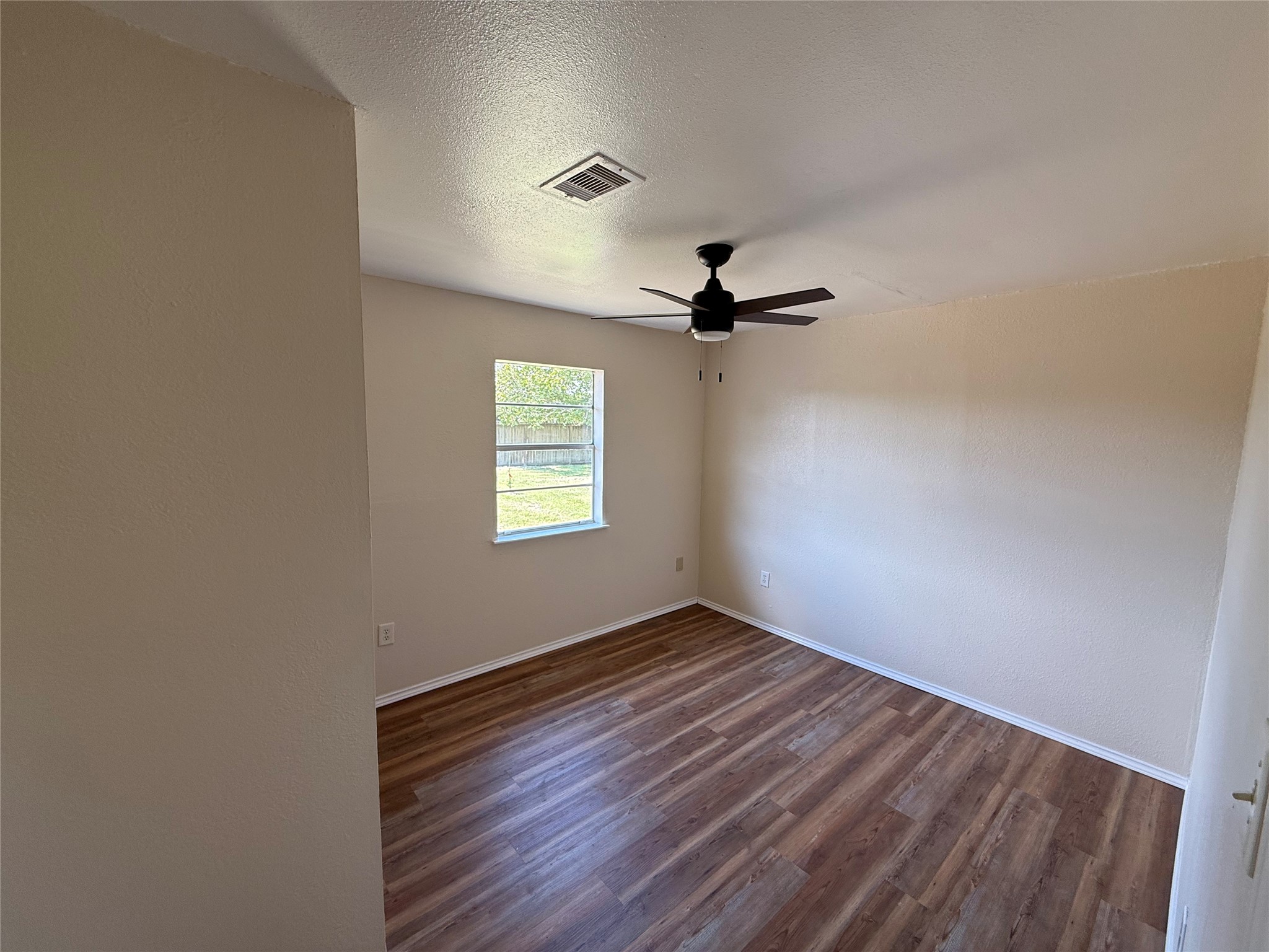 Room featuring wood-look flooring, two-tone walls, and a ceiling fan.