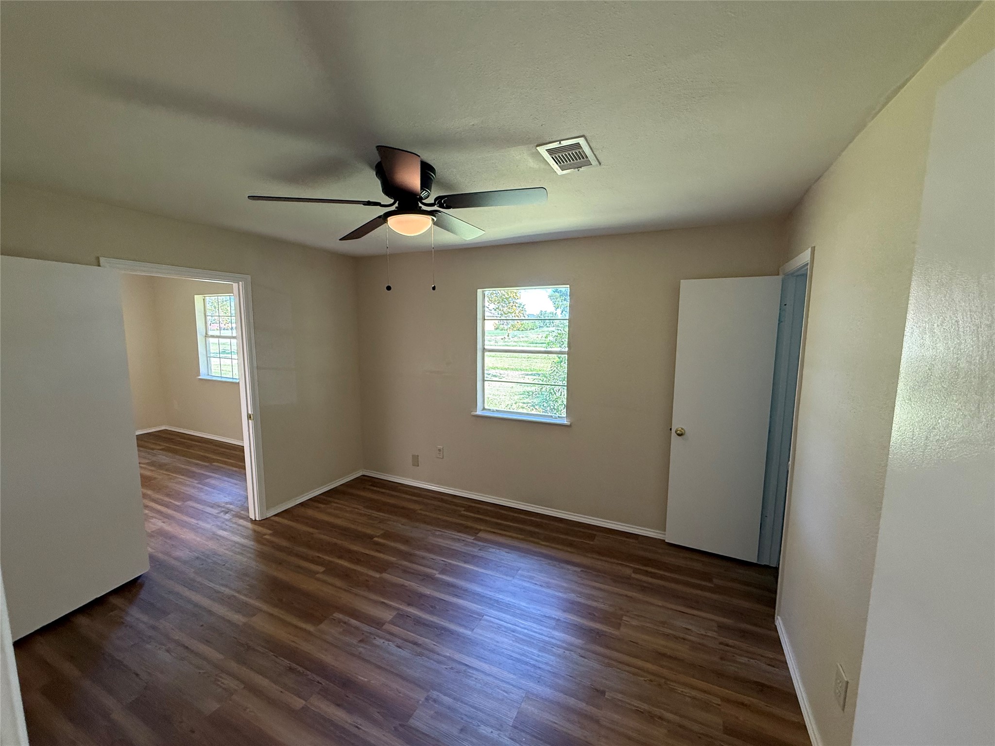 Alternate view of the living area showing wood-look flooring and access to adjoining rooms.