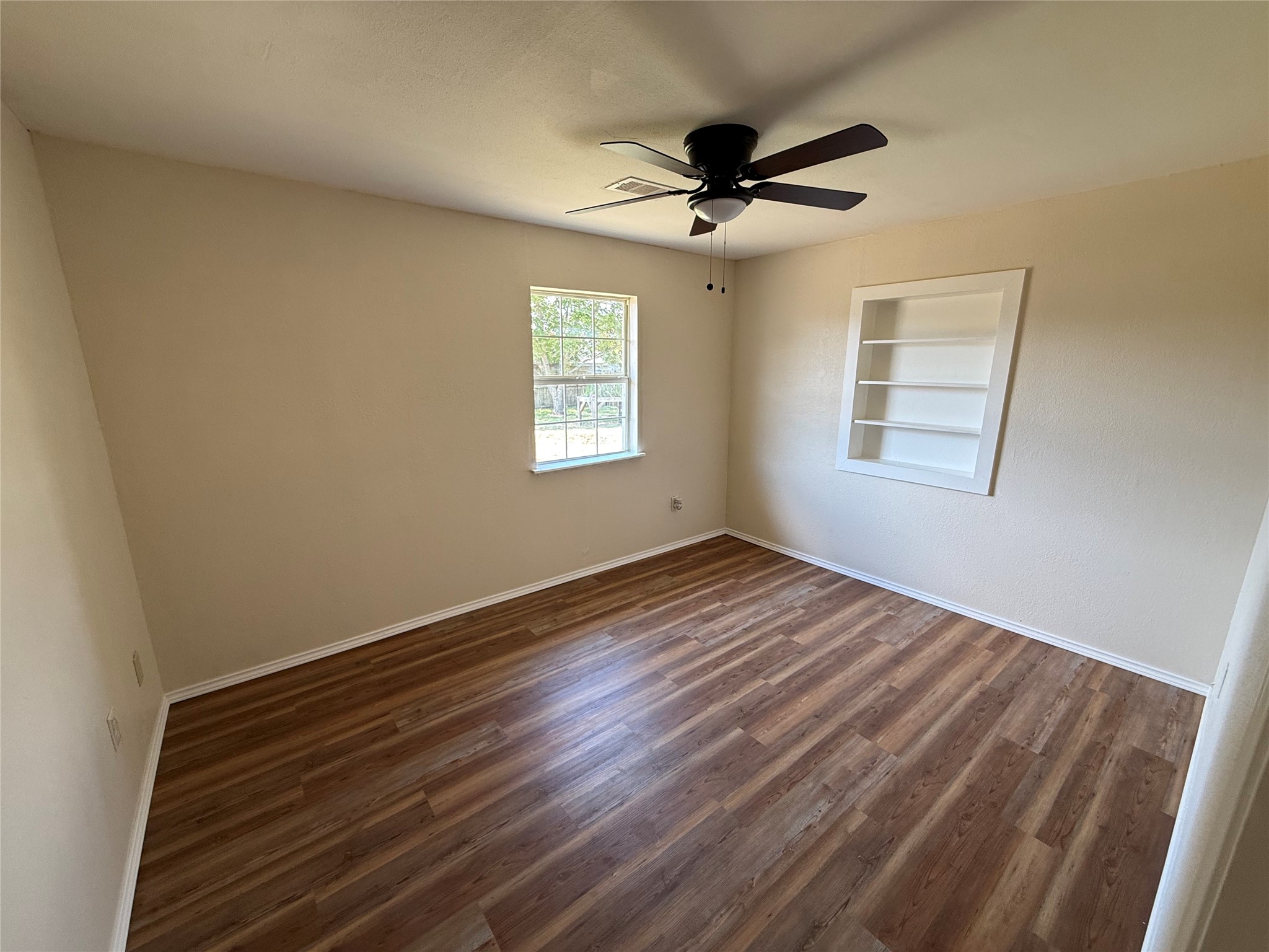 Room with wood-look flooring, two windows, and a ceiling fan.