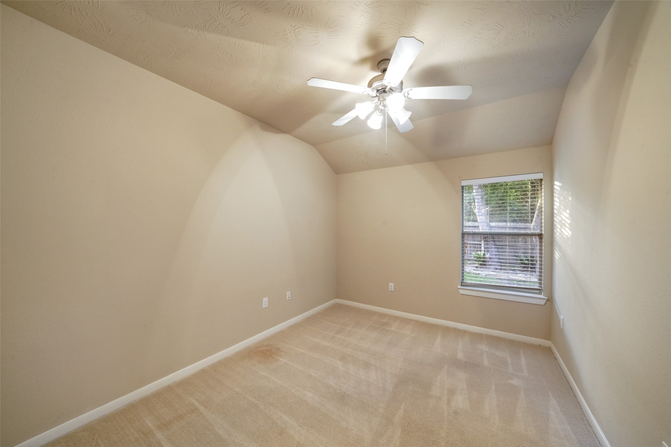 Secondary bed with carpet, ceiling fan and overlooks the backyard.