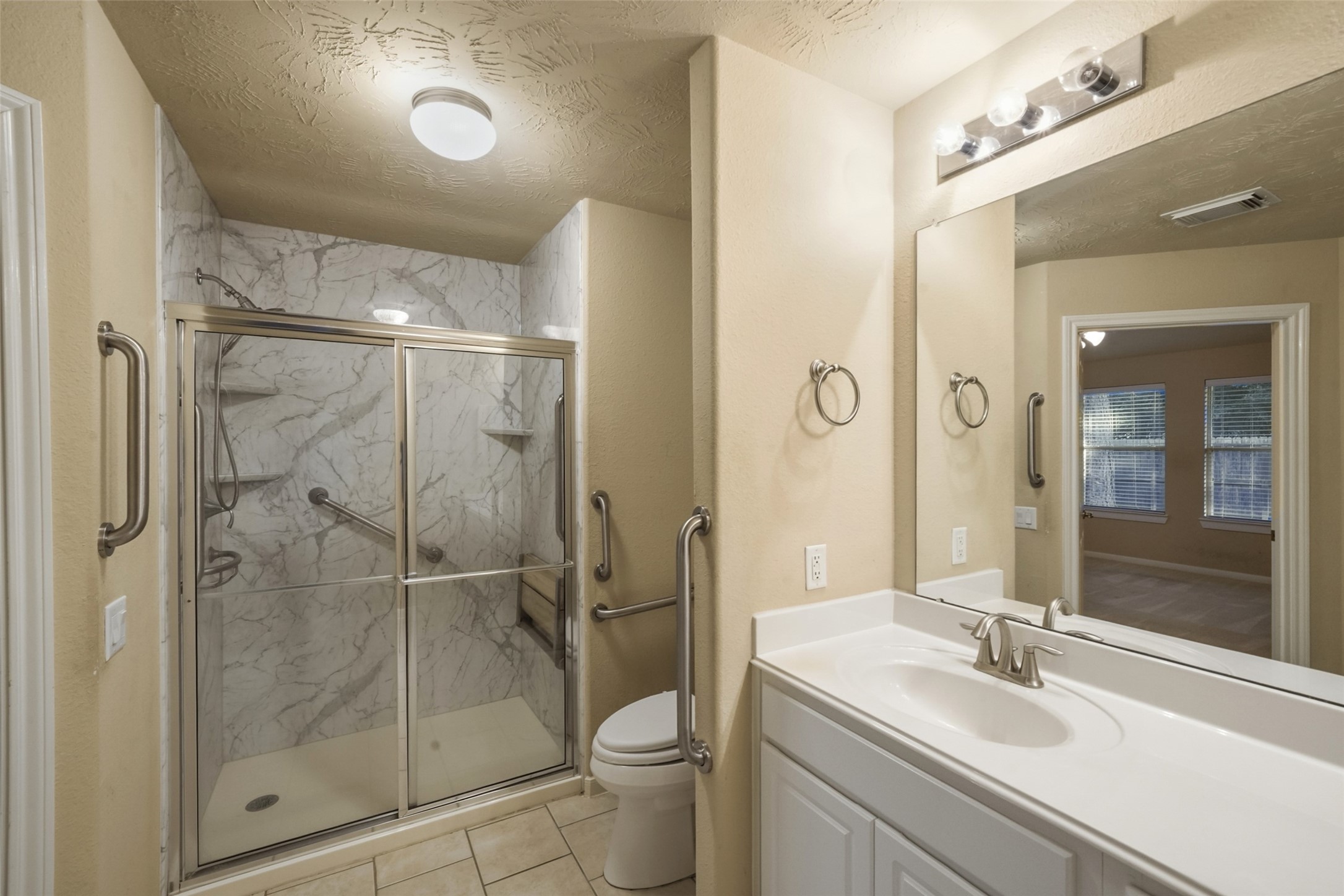 Primary is equipped with a walk in shower. Notice the grab bars by the entry door, commode and inside the shower. Perfect for anyone who may have mobility issues.
