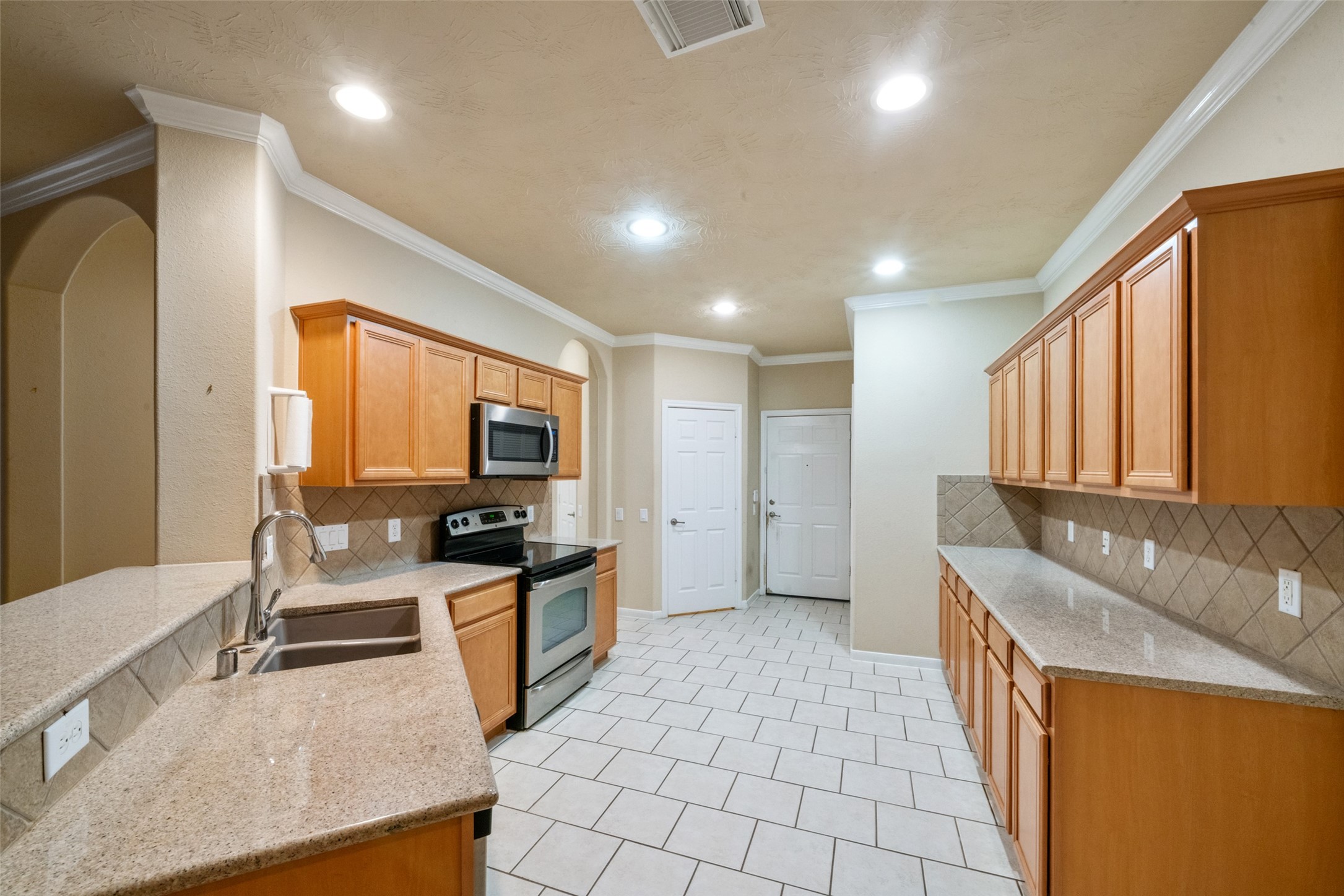 Notice the long counter space and expansive cabinets. The walk in pantry and garage entry door can be seen at the back of the photo.