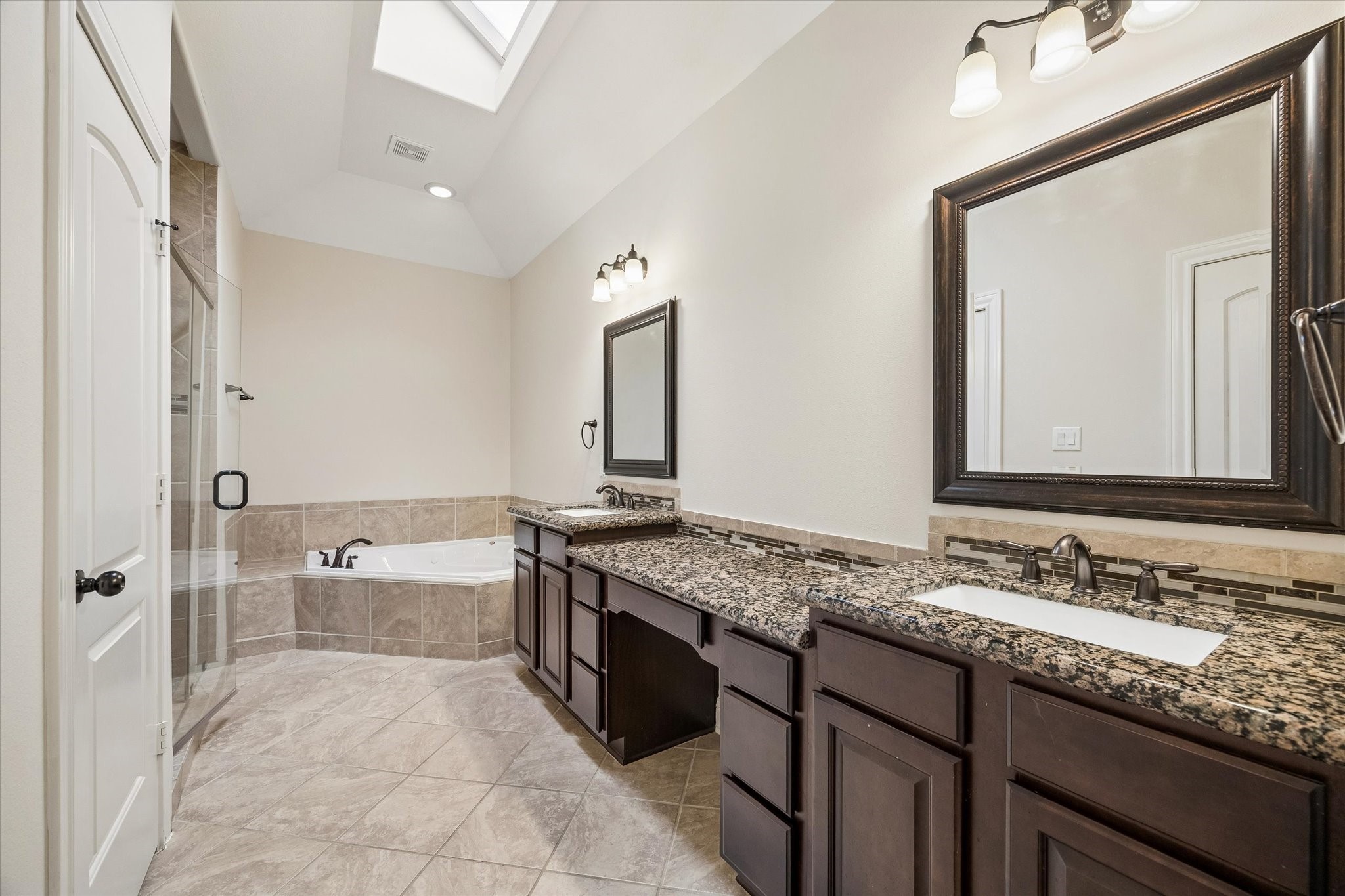 Luxurious primary bath with dual vanities, soaking tub, and separate shower.