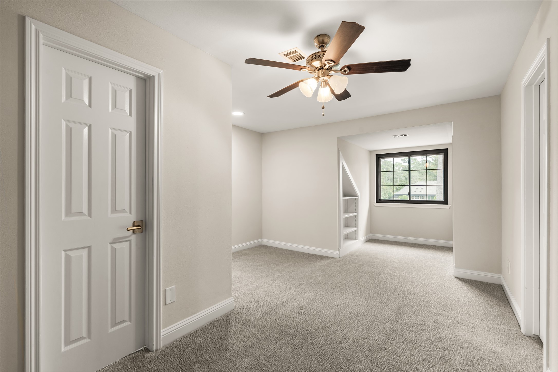 A charming flex space upstairs with built-in shelving and natural light offers a versatile setting for reading, studying, or creating a quiet retreat.