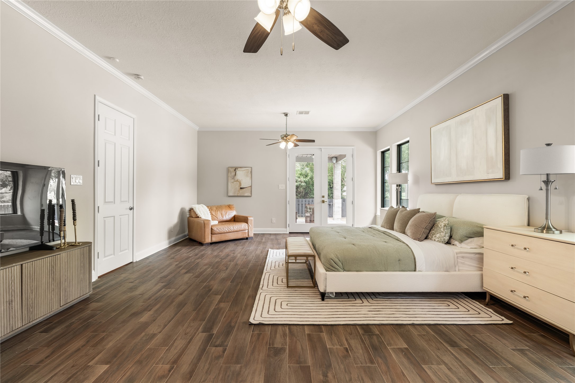 The primary bedroom offers an airy, refined atmosphere with abundant room for a sitting area and French doors extending the living space outdoors.