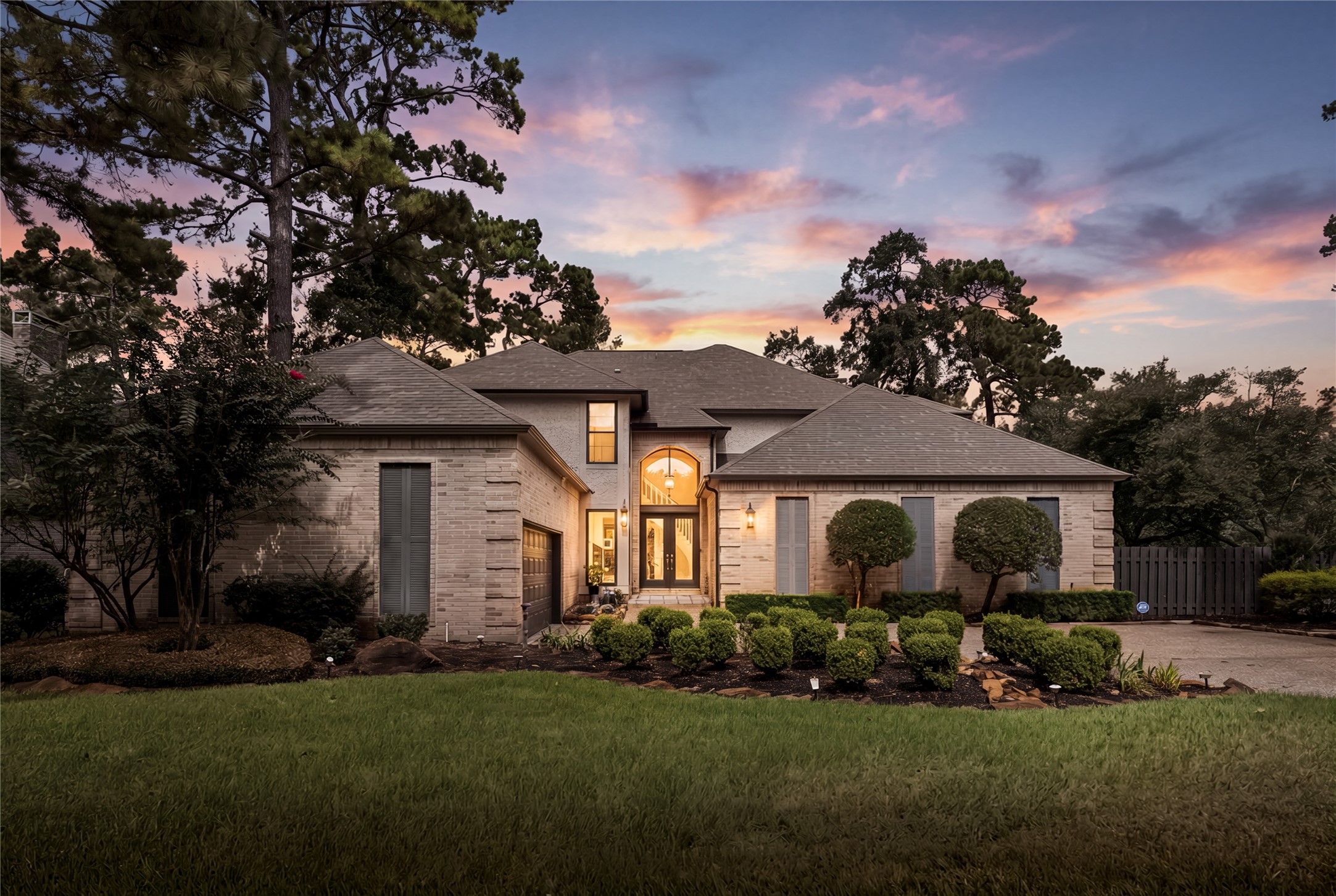 A striking twilight arrival showcases timeless brick architecture, mature landscaping, and the warm, welcoming glow of this beautifully updated residence.