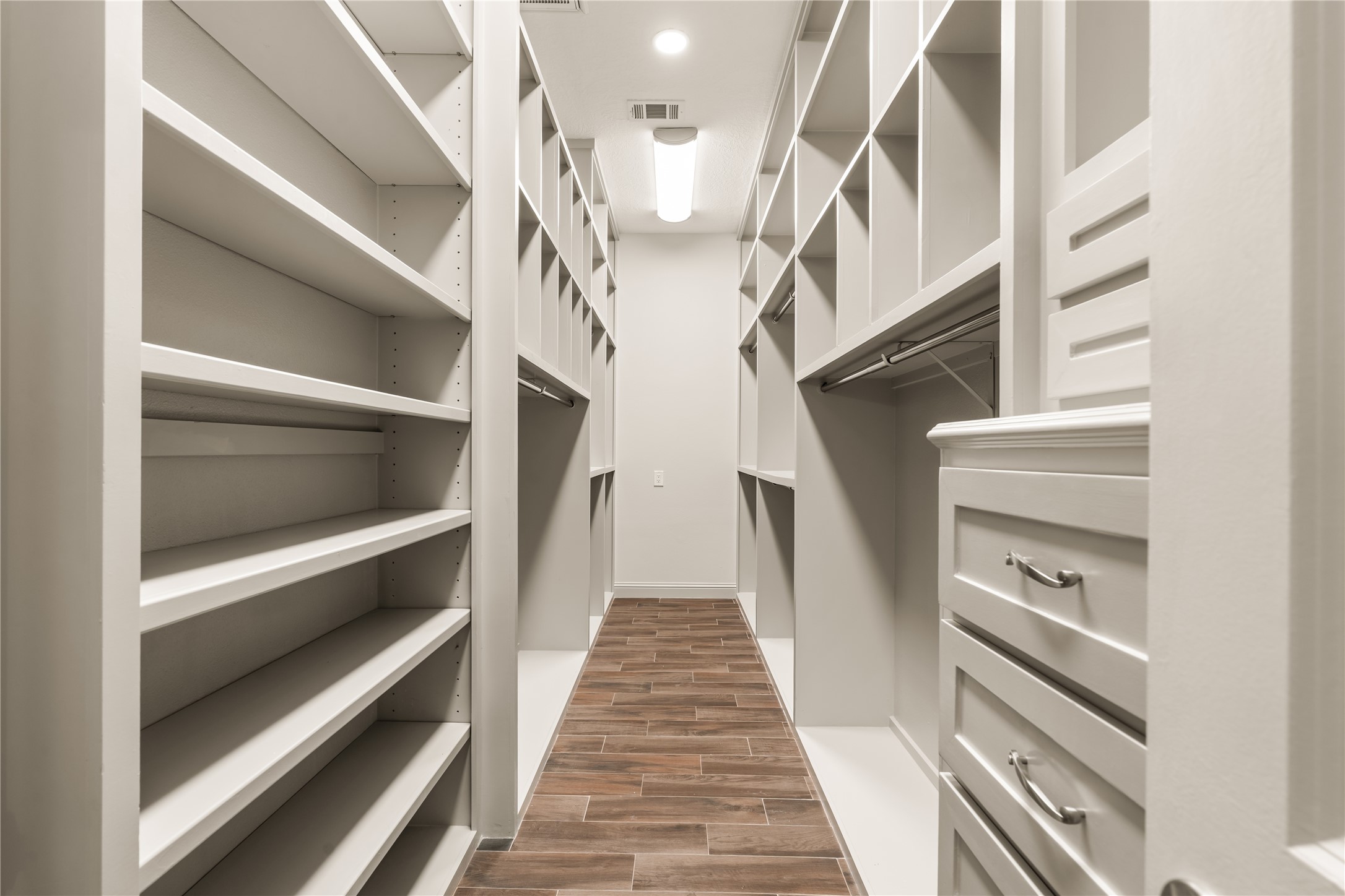 Exceptional walk-in closet with extensive custom built-ins, shelving, hanging space, and drawers for beautifully organized storage