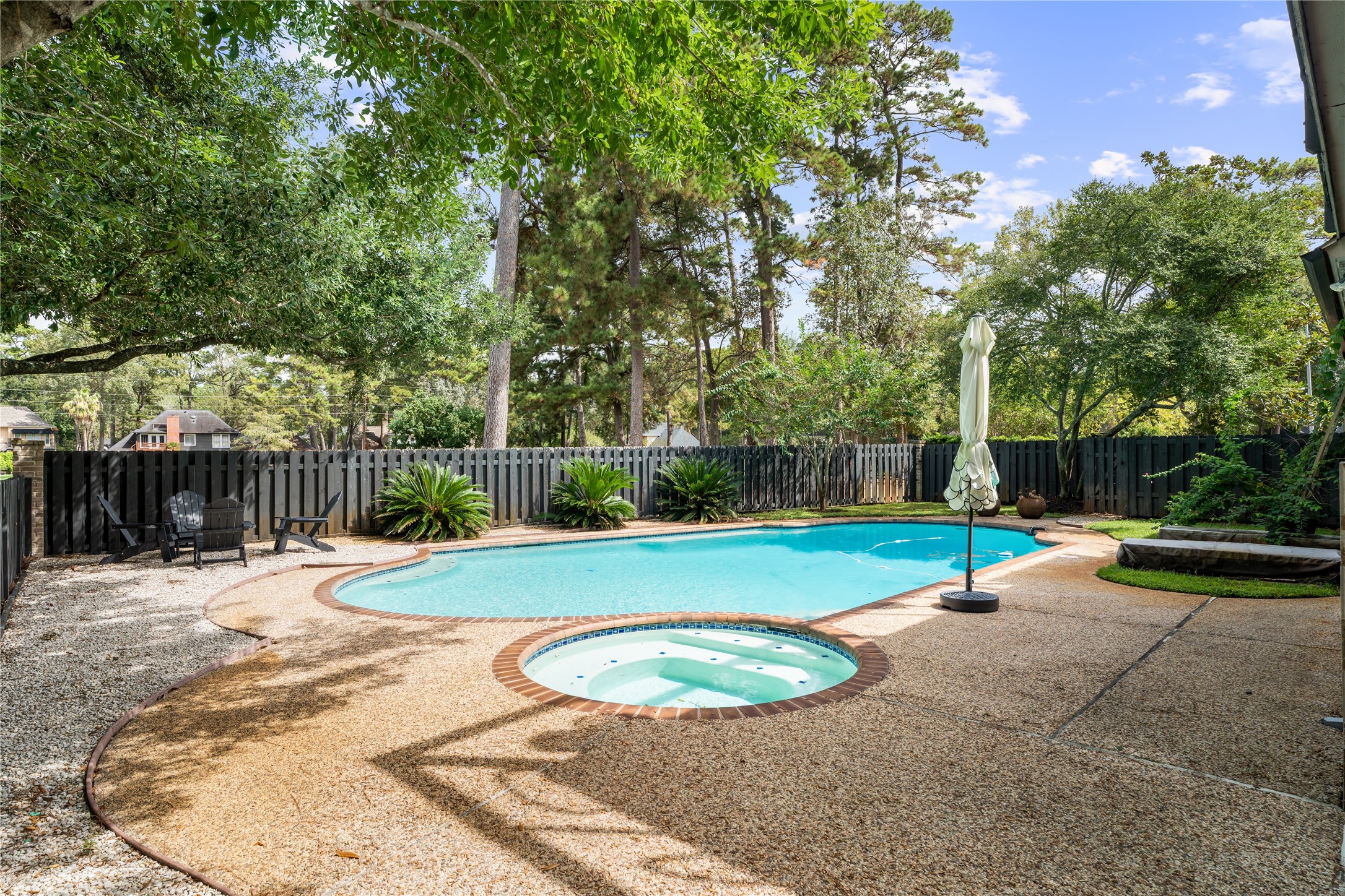 The private backyard showcases a resort style pool and spa surrounded by mature trees and lush landscaping, with generous poolside space for lounge seating, entertaining, and soaking up the sun.