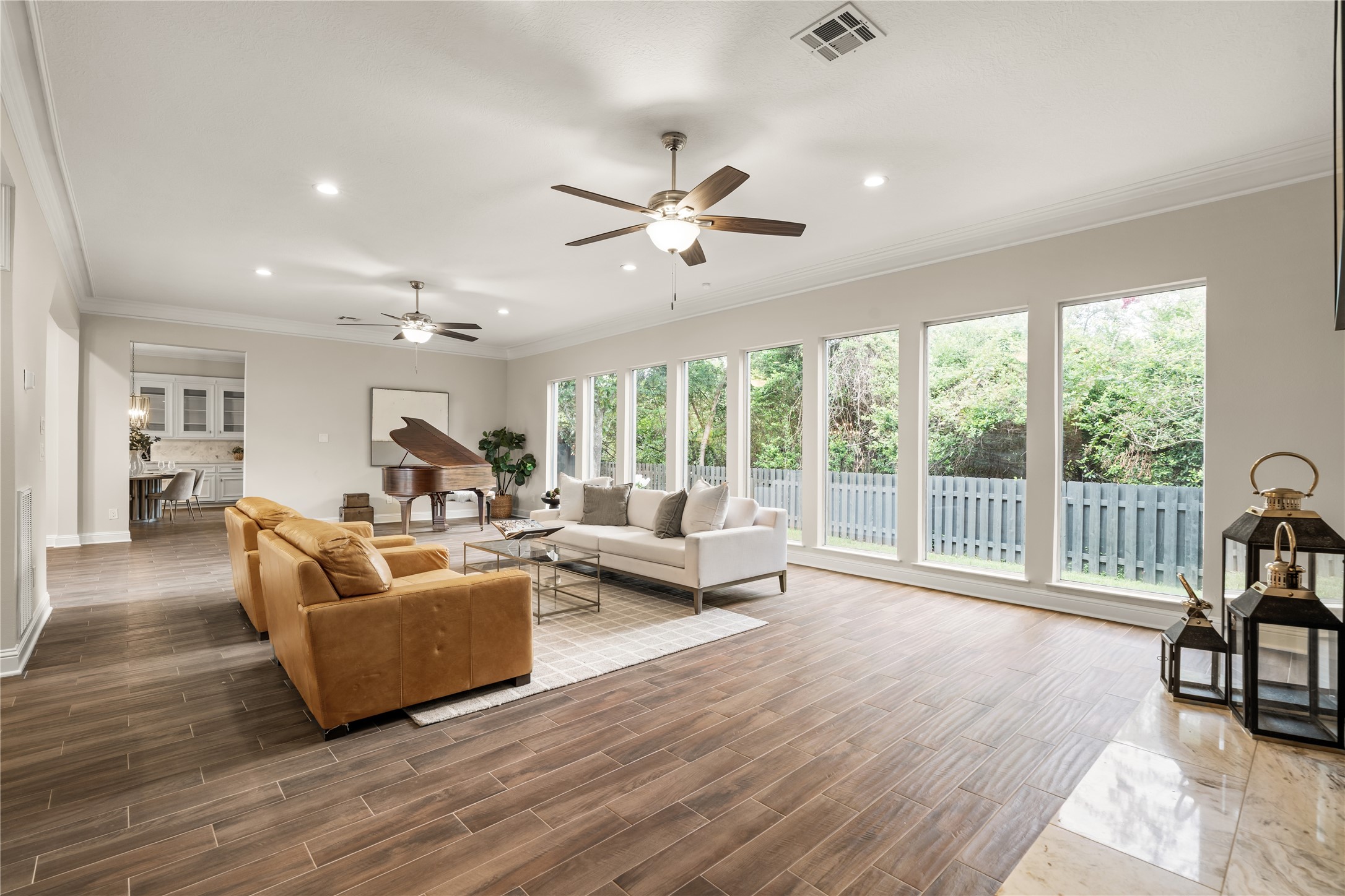A dramatic wall of windows bathes the expansive living room in natural light, creating an airy, sophisticated setting with beautiful views of the surrounding greenery.