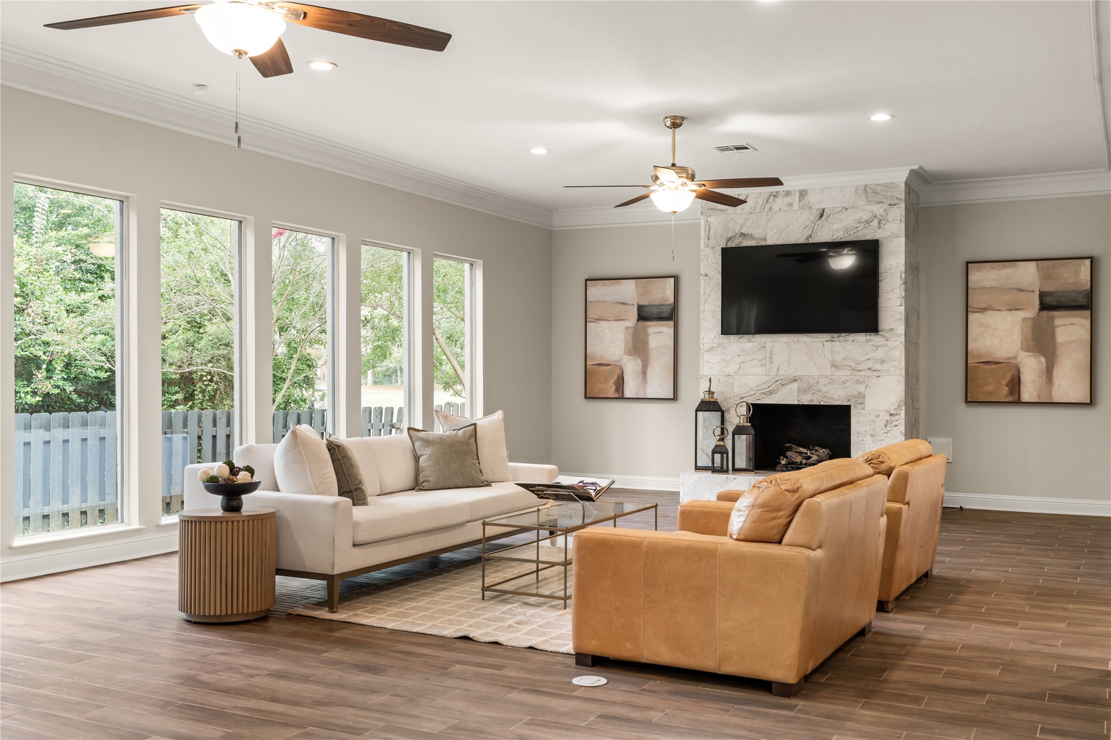 The marble-clad fireplace creates a sophisticated focal point, complemented by a dramatic wall of windows and beautifully curated living spaces.