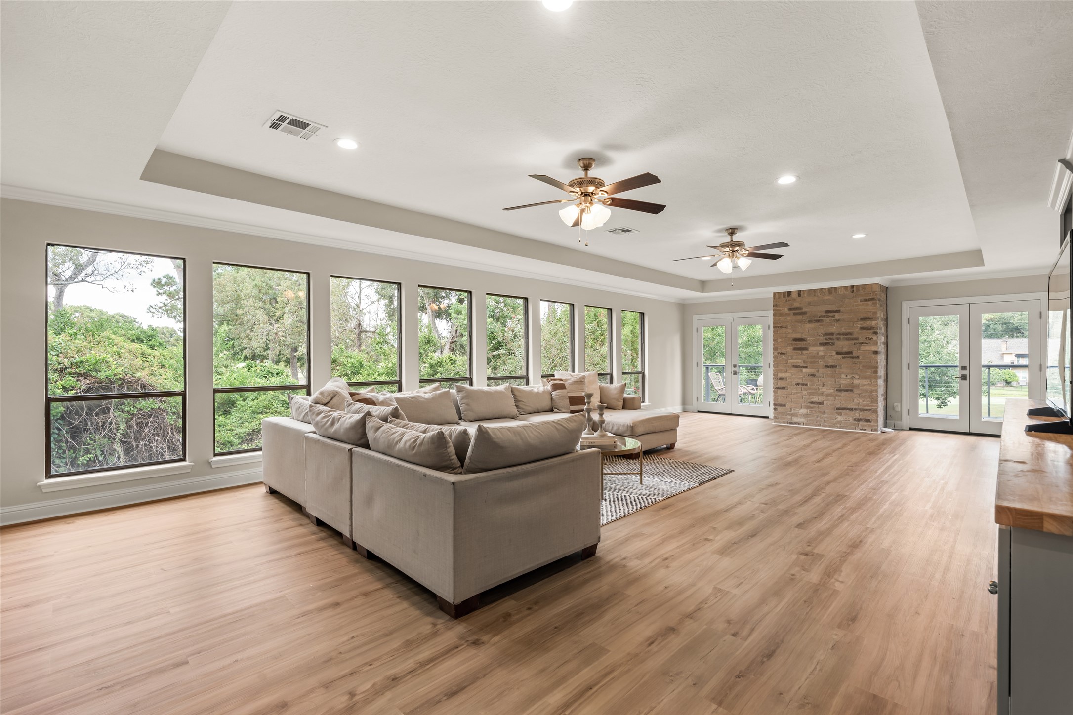 An impressive upstairs family room is wrapped in natural light and treetop views, with updated LVP flooring creating a polished setting for relaxing or entertaining.