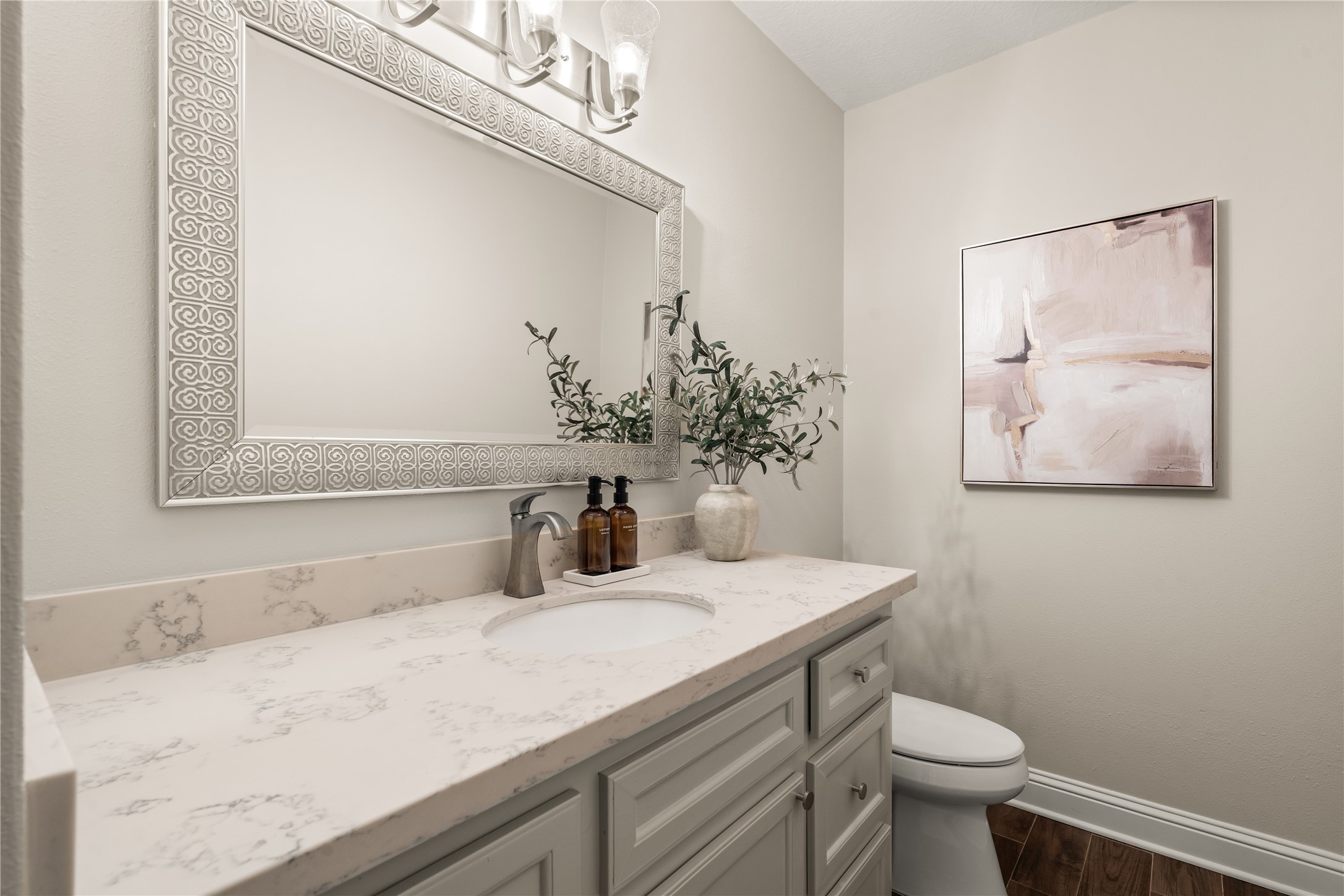 A sophisticated powder bath pairs an extended vanity with elegant finishes and a statement mirror, creating a polished space for guests.