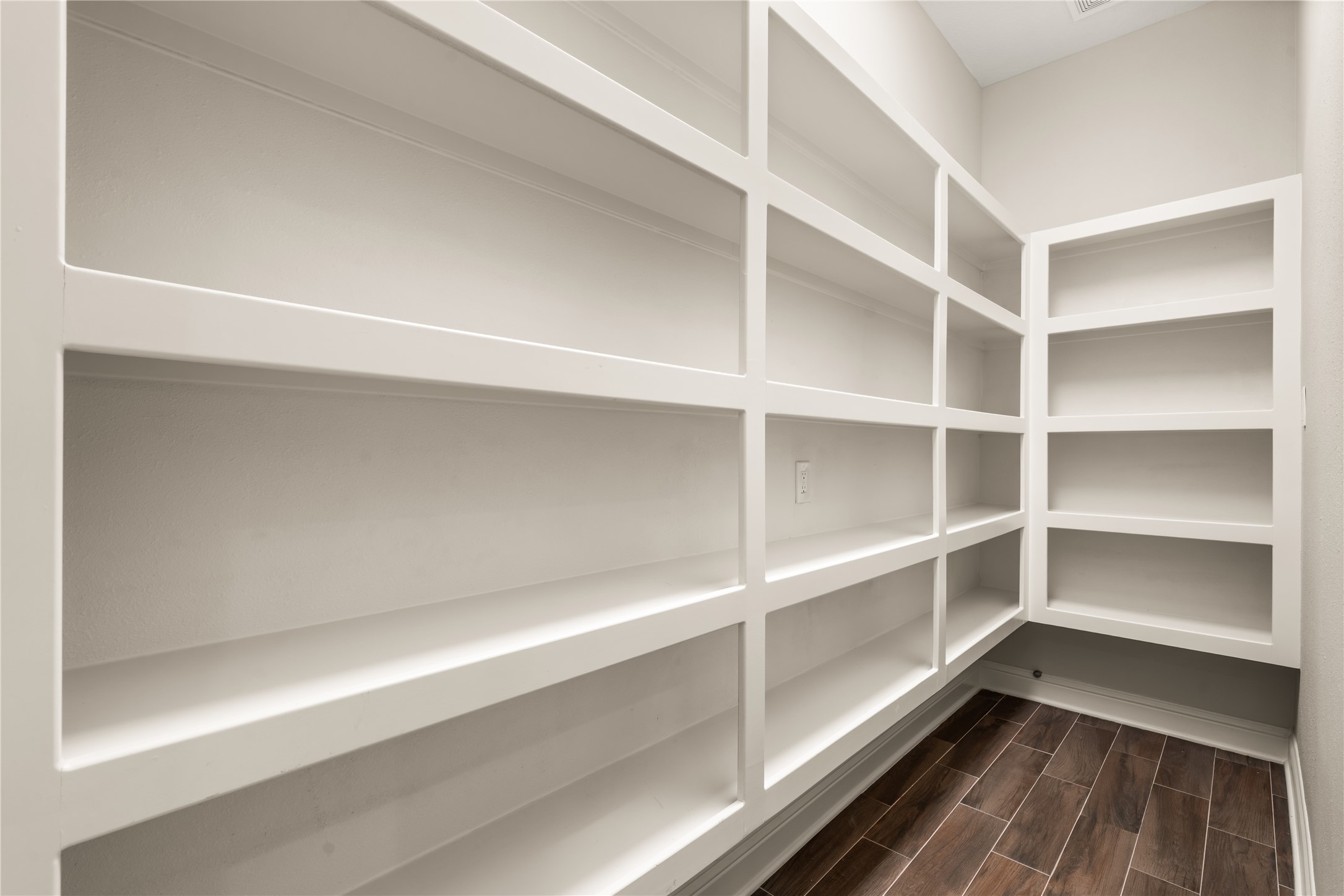 A spacious walk-in pantry offers exceptional storage with extensive built-in shelving, keeping everyday essentials beautifully organized.