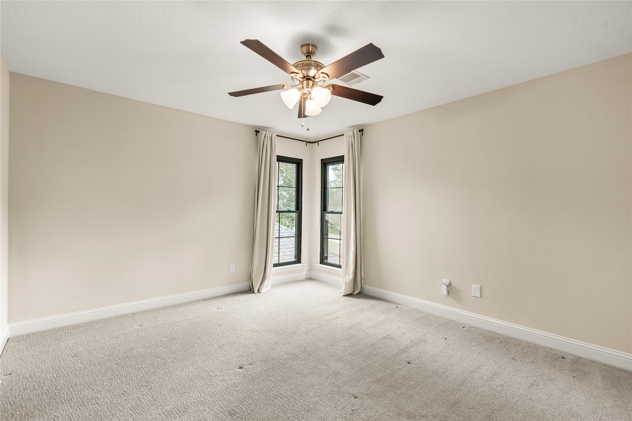 This generously sized secondary bedroom is filled with natural light from corner windows and offers ample flexibility for guests, family, or a private retreat.