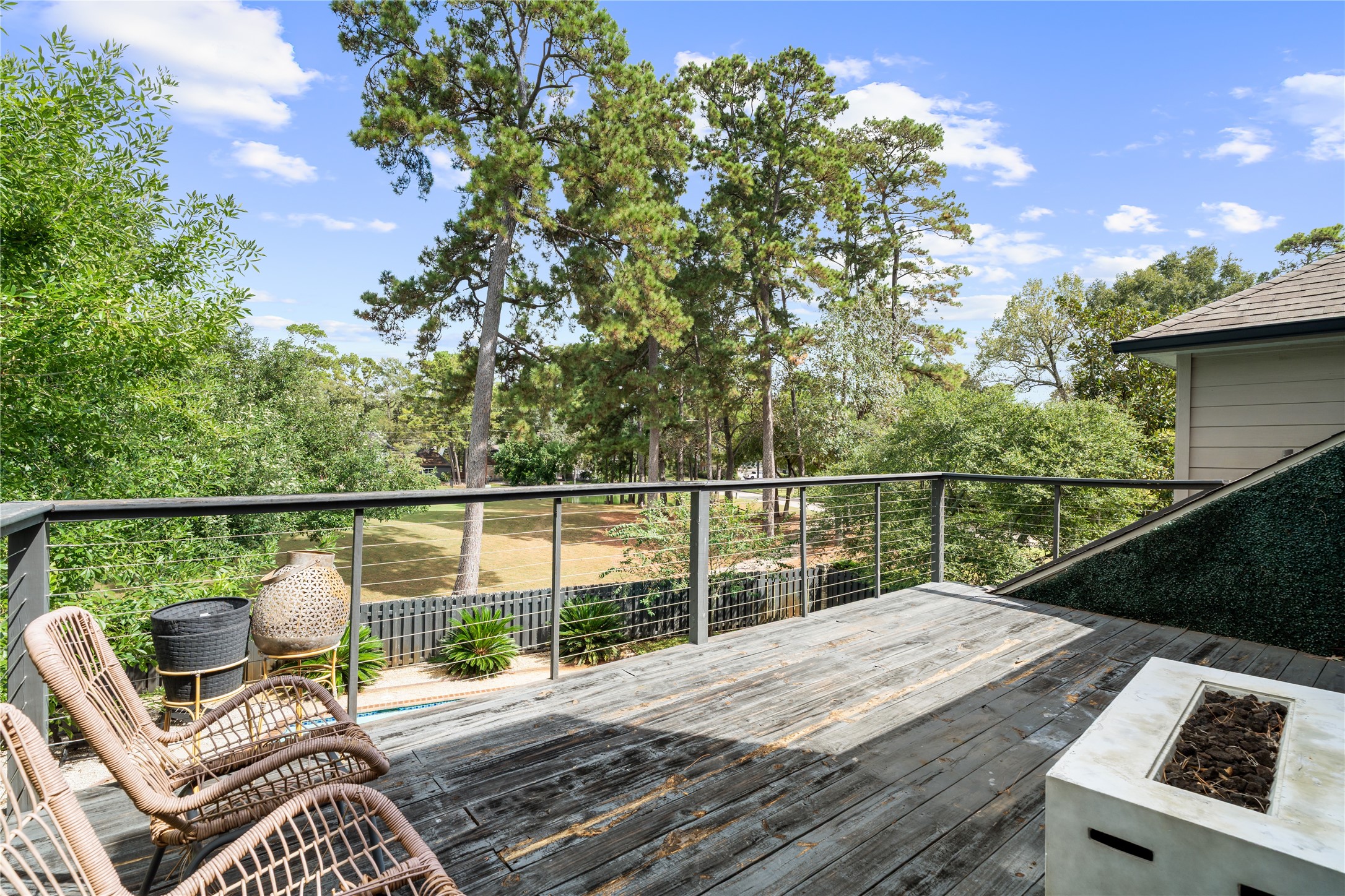 An expansive elevated terrace creates an exceptional outdoor escape surrounded by mature trees, with plenty of room for lounge seating around the fireplace, entertaining, and enjoying the peaceful views.