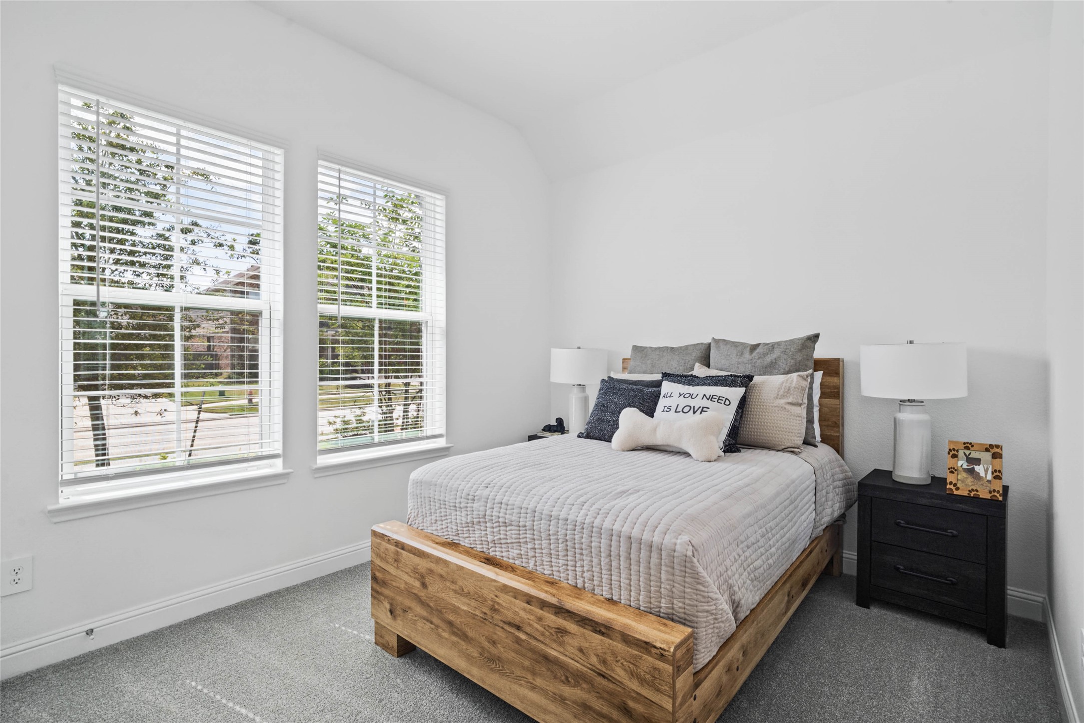 Tucked peacefully in the front of the home is this guest suite, which offers a bright layout with neutral finishes and natural light. Featuring plush carpeting, large windows with blinds, and an en-suite secondary bathroom.