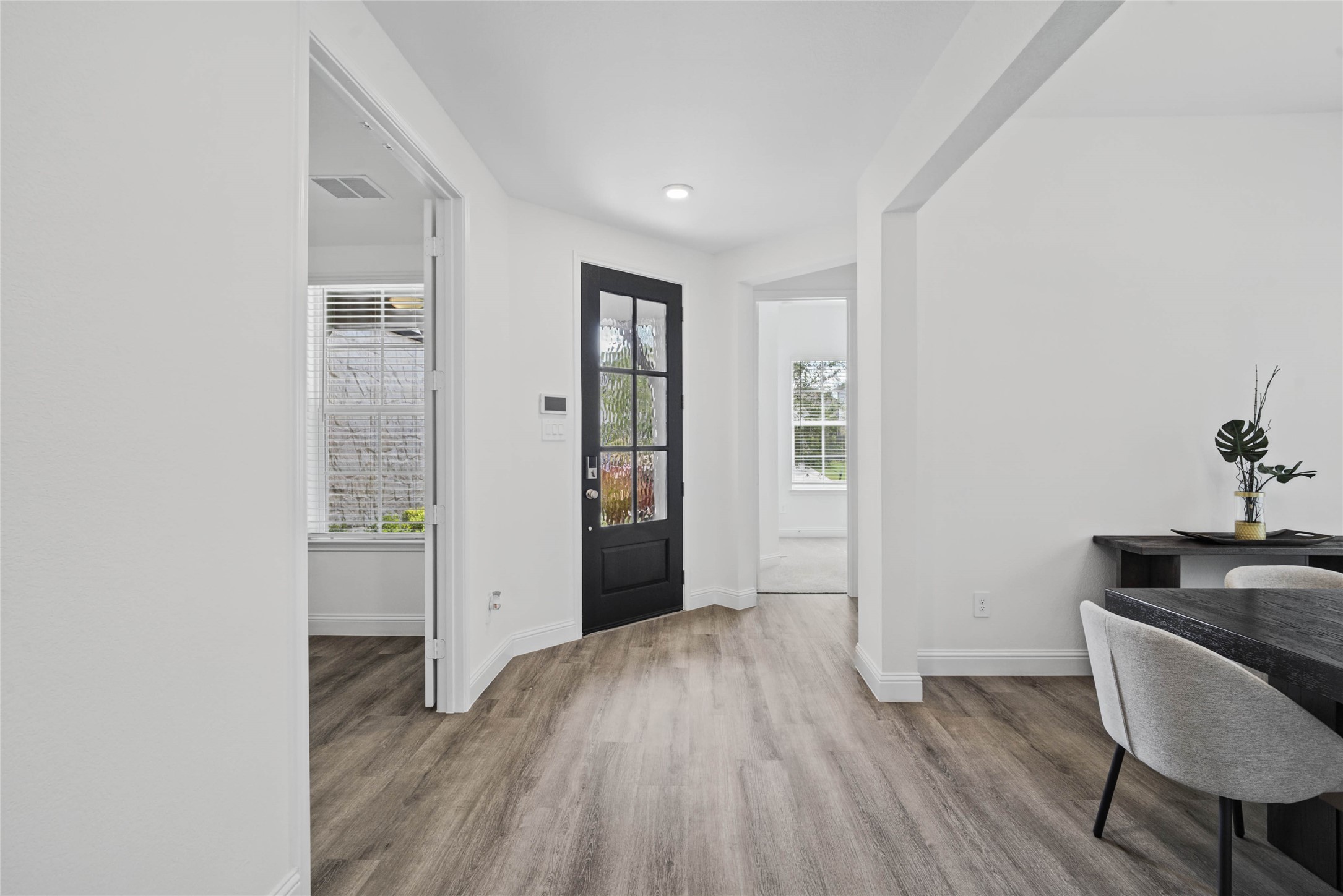 An inviting entrance opens up to an open-concept layout, seamlessly connecting the entry to the living areas with durable luxury vinyl plank flooring and striking architectural details.
