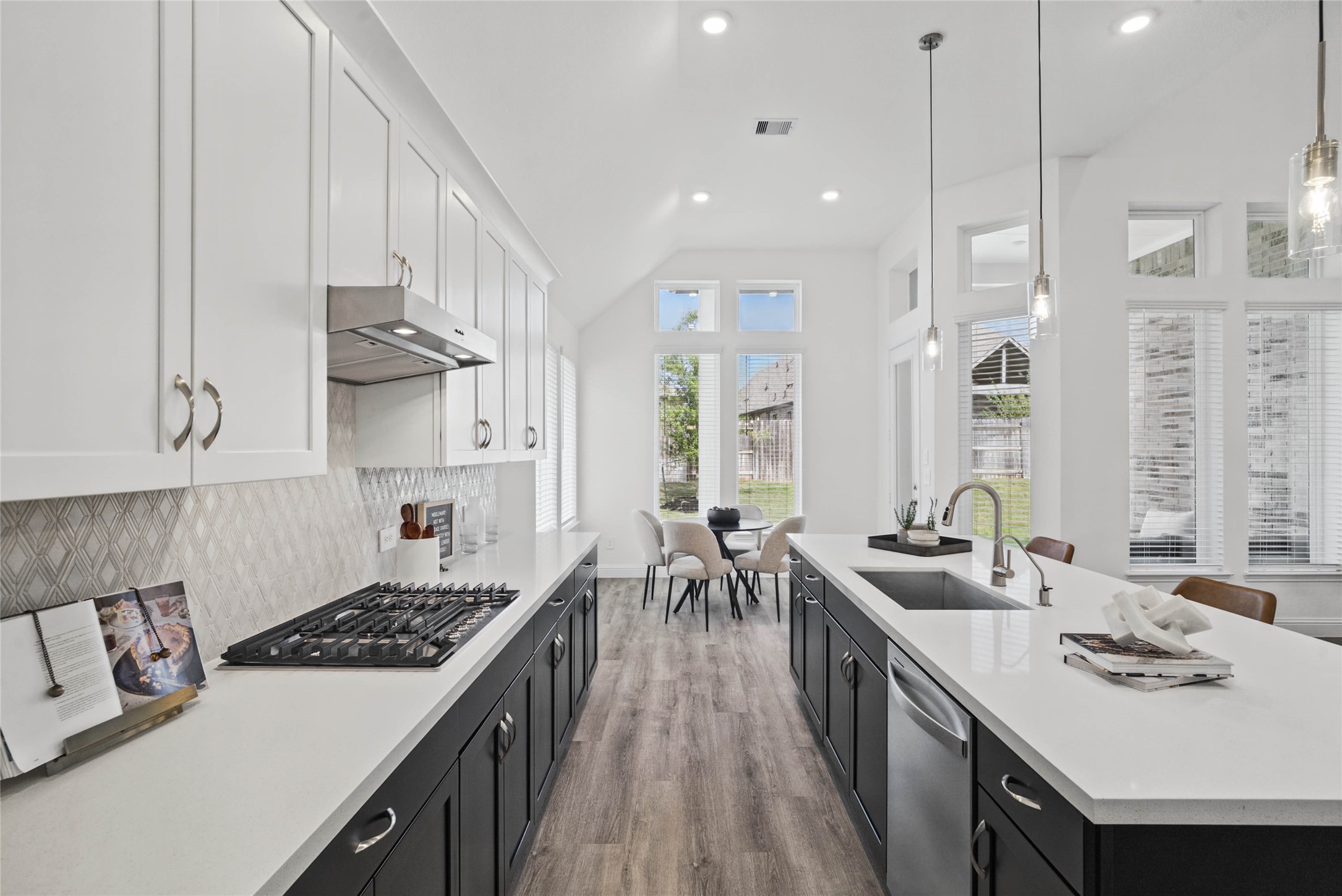 This gourmet kitchen features a modern tuxedo-style design, pairing sleek matte black base cabinets with crisp white uppers. The transitional space is anchored by a sprawling center island topped with premium quartz countertops, offering an expansive prep area and integrated stainless steel undermount sink.