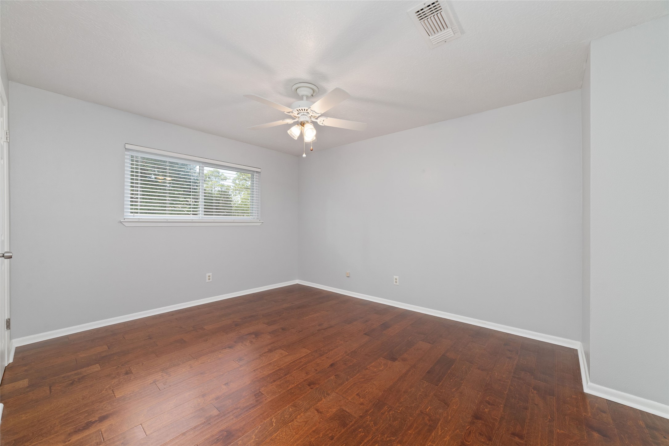 Spacious upstairs bedroom with rich wood flooring, backyard views, a walk-in closet, and convenient access to a shared Jack-and-Jill bathroom.  This bedroom measures appox 14x11.