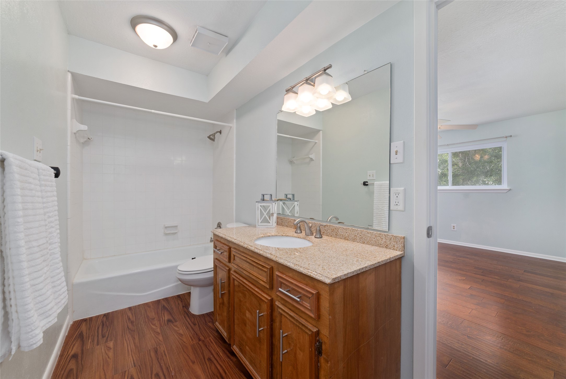 Private en-suite bathroom serving the upstairs secondary bedroom features a spacious wood vanity with granite countertop, brushed nickel fixtures, and tub/shower combination.