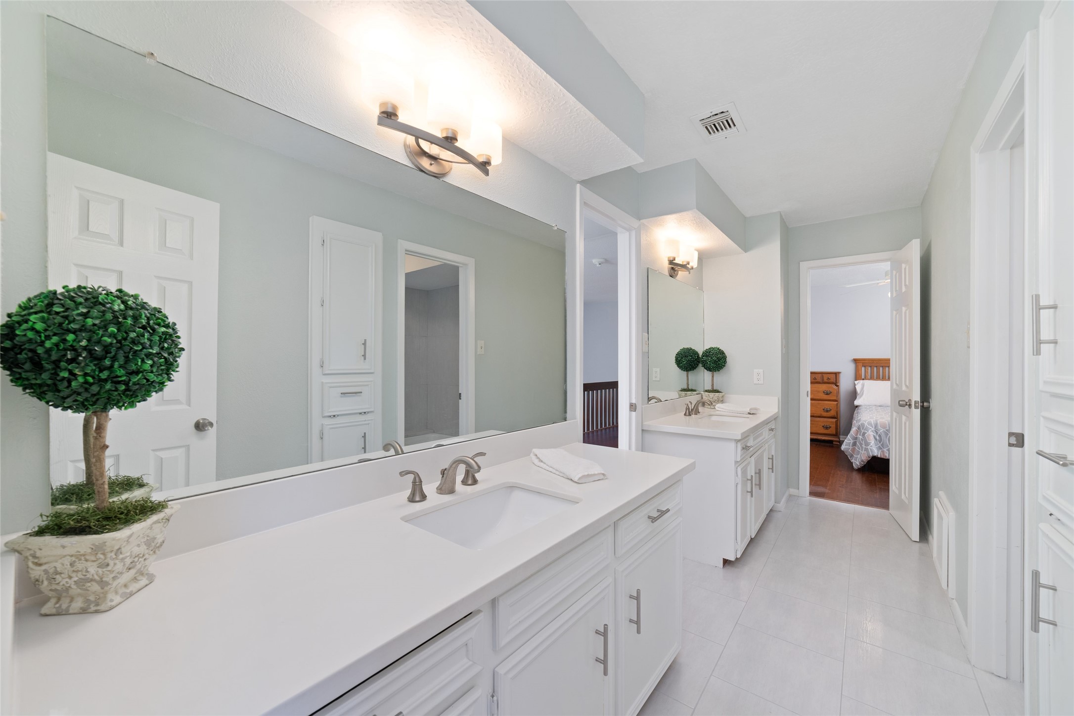Designed with convenience in mind, this spacious Jack-and-Jill bathroom features separate vanity areas for each bedroom, complete with individual sinks, generous counter space, mirrors, and storage. A shared tub/shower and toilet area connects the two spaces