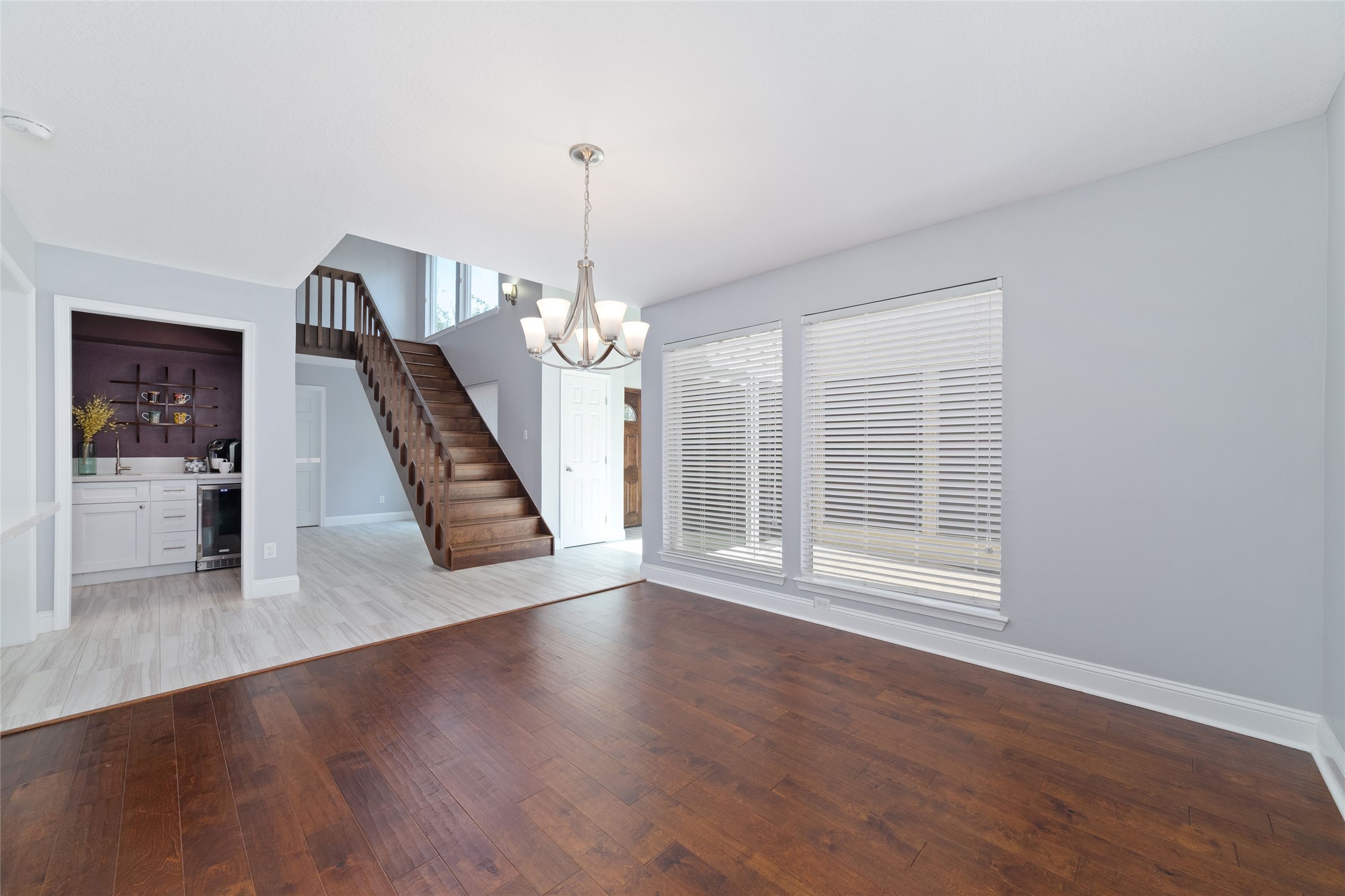 Another perspective highlights the home's wonderfully connected floor plan. Natural light streams through the Dining Room windows overlooking the private courtyard, while the beautiful wood staircase adds architectural warmth. Just beyond, a charming coffee bar offers a convenient spot to start your mornings.