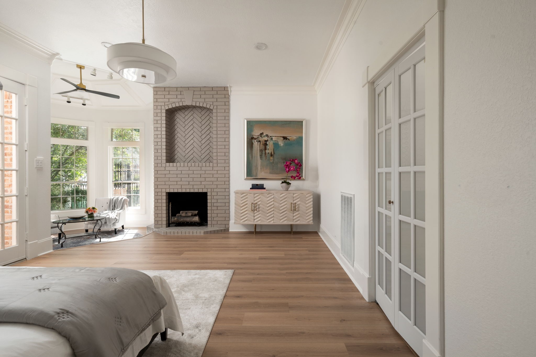 The primary bedroom combines generous scale with a flexible layout designed for both relaxation and everyday living. French doors provide direct access to the patio and surrounding outdoor areas. Updated lighting, neutral finishes, and oversized windows continue throughout the suite.