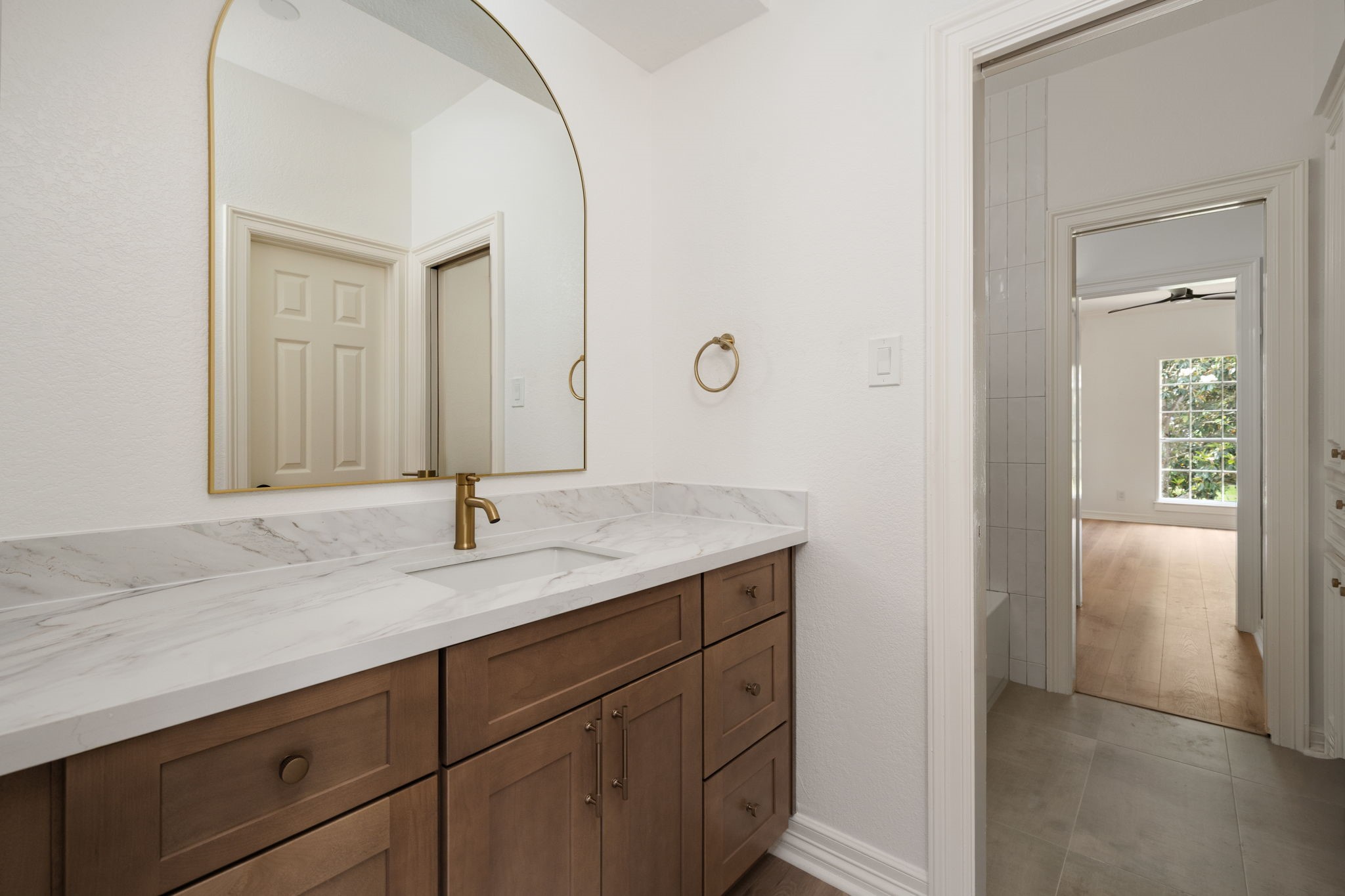 Renovated secondary bathrooms feature updated vanity cabinetry, quartz surfaces, and frameless glass shower enclosures. Designer lighting and contemporary fixtures elevate the spaces while maintaining everyday functionality. Clean finishes and integrated storage continue throughout the bathrooms.