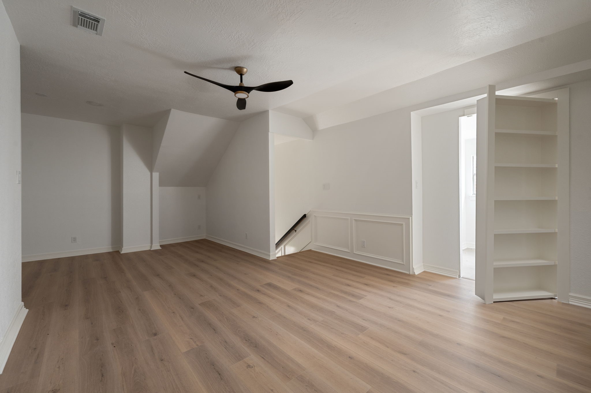 The second-floor landing offers a flexible living space overlooking portions of the homes main level. A hidden bookcase entry provides access to the secondary upstairs utility room, complementing the main utility area located on the first floor. Updated flooring, recessed lighting, and open sightlines create a bright and functional environment.