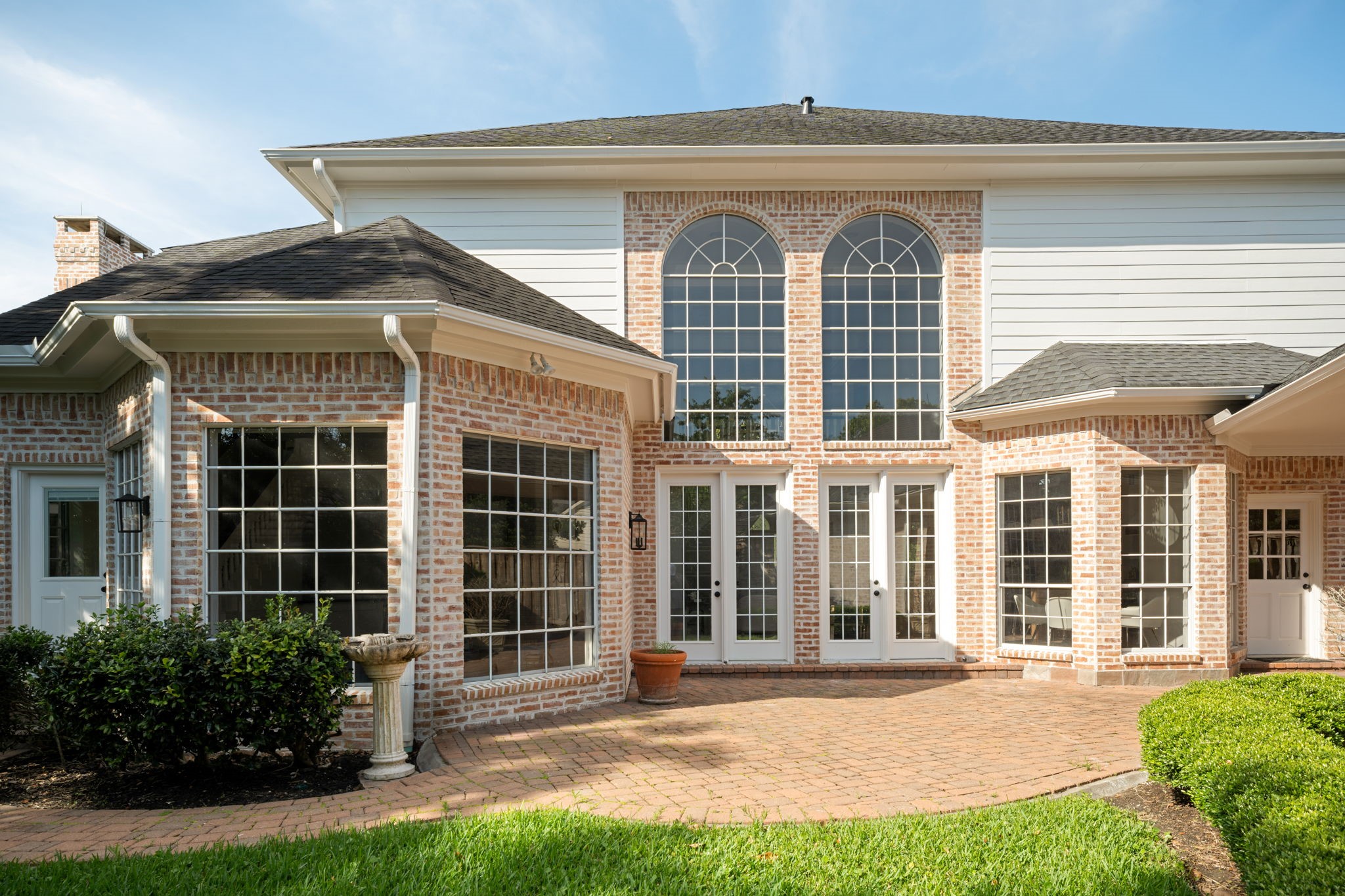 The rear elevation features expansive windows and soaring ceiling heights reflected throughout the homes design. Multiple access points connect the interior spaces to the backyard and patio areas. The layout was designed to maximize natural light across the main living spaces.