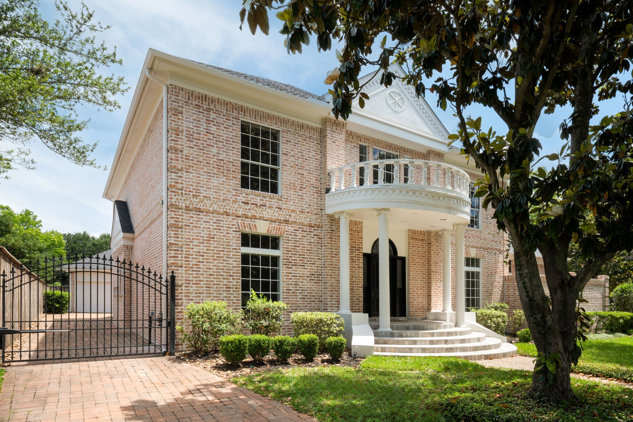 The front elevation combines classic architectural symmetry with expansive windows and a sweeping covered entry framed by mature trees and updated landscaping. A gated brick paver driveway creates a welcoming approach while adding privacy and functionality to the property. Positioned on a prominent corner lot within Sweetwater Section 1 in Sugar Land.