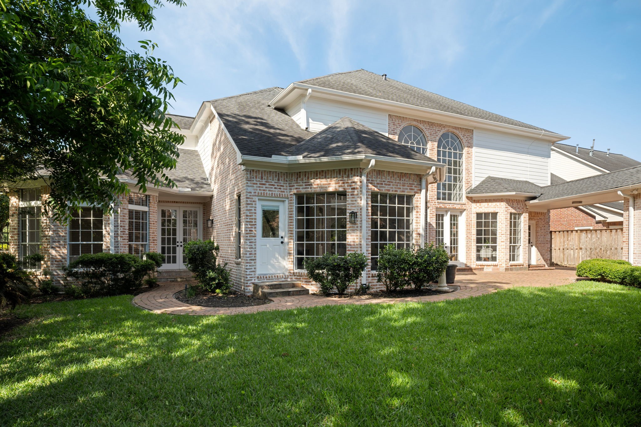 The rear exterior balances classic architecture with updated presentation and established landscaping throughout the property. Expansive windows, elevated ceilings, and courtyard-style outdoor spaces reinforce the homes indoor-outdoor connection. Positioned within Sweetwater Section 1 in the heart of Sugar Land.