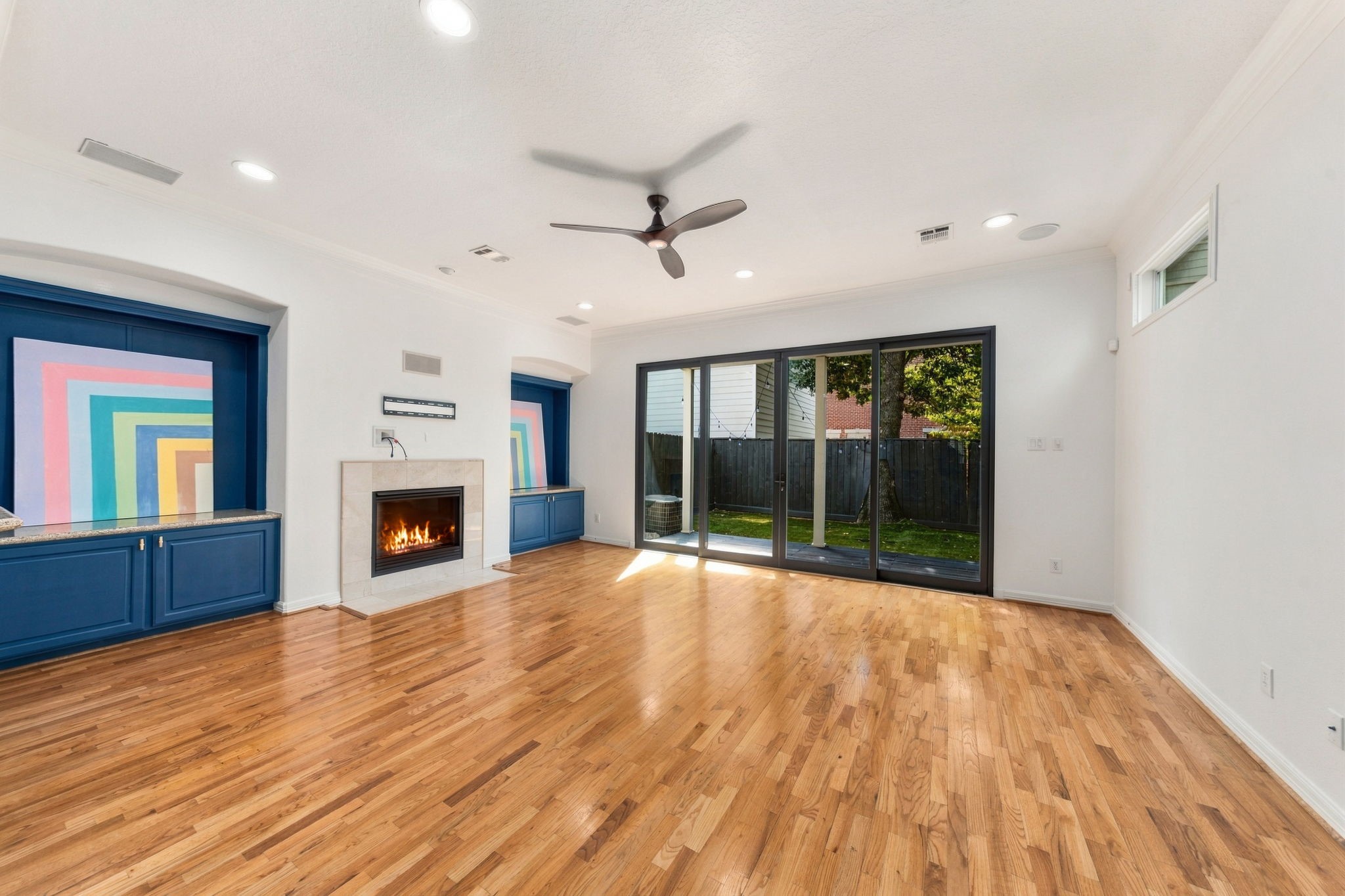 Another perspective highlighting the fireplace, distinctive blue built-in cabinetry & wide sliding glass doors overlooking the backyard.