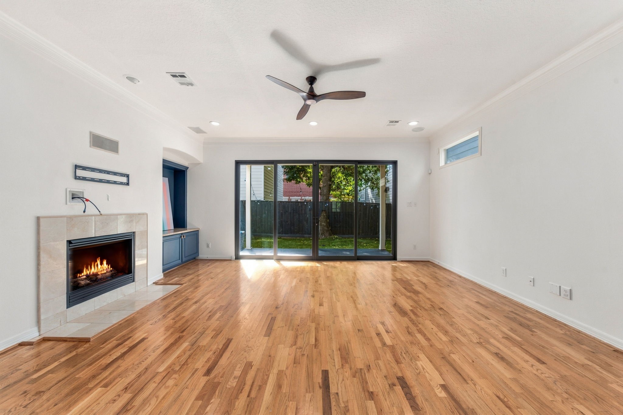 A closer look at the living room's hardwood flooring, fireplace & direct access to the outdoor living area.