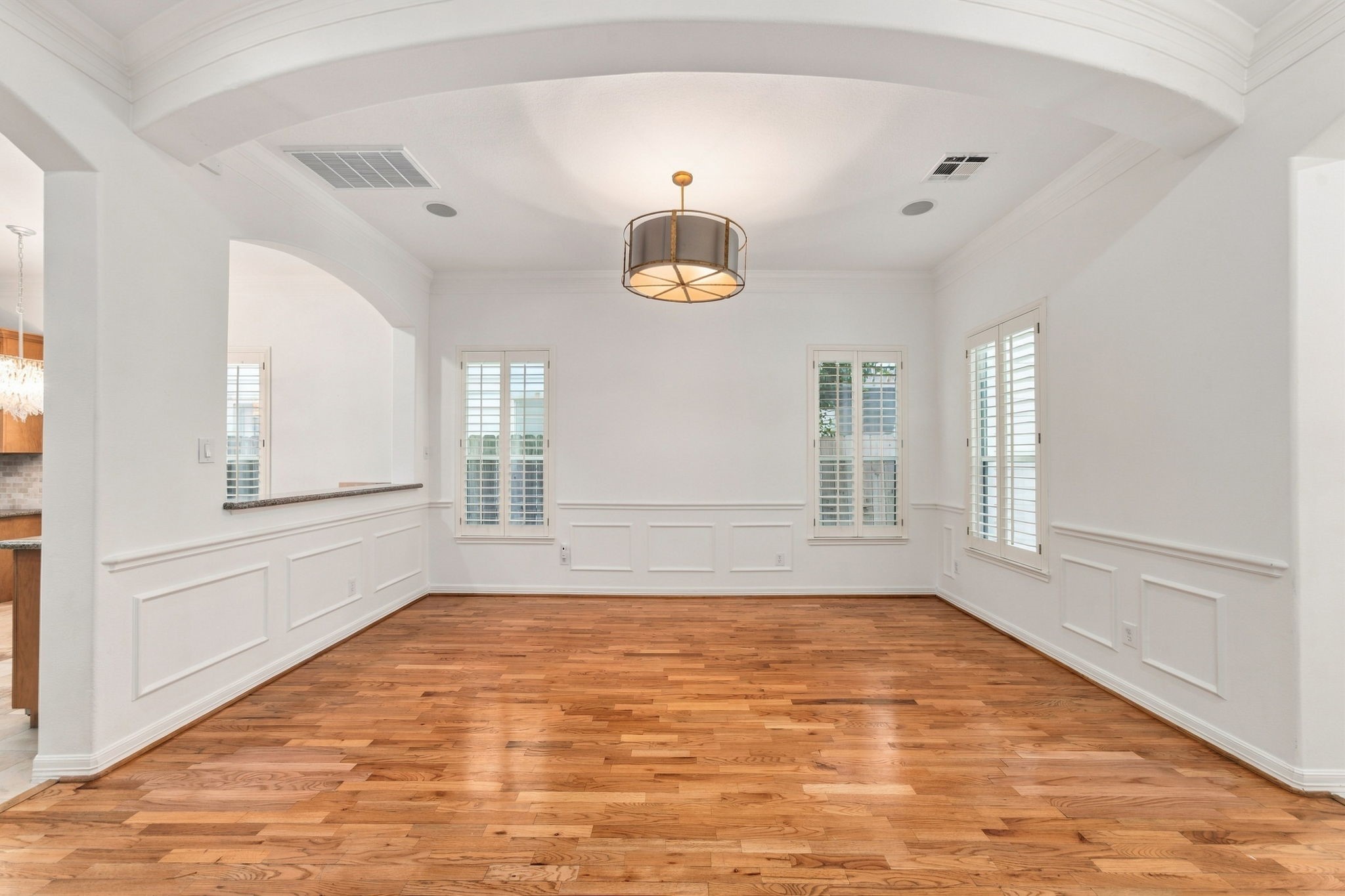 A lovely view of the curved staircase, rich hardwood floors & architectural archways that bring character to the main level.