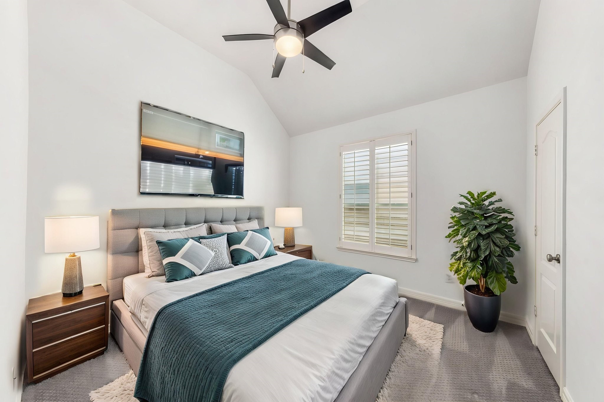 This bedroom features a vaulted ceiling, plantation shutters & ceiling fan, with the versatility to serve as a home office. Virtually staged to illustrate furniture placement.